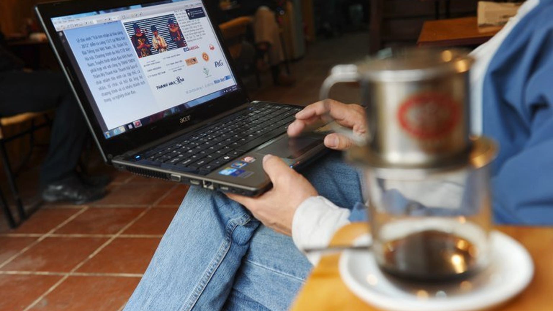 A man reads online news with his laptop at a coffee shop in downtown Hanoi on January 15, 2013. Communist Vietnam is to ban bloggers and social media users from sharing news stories online, under a new decree seen as a further crackdown on online freedom.