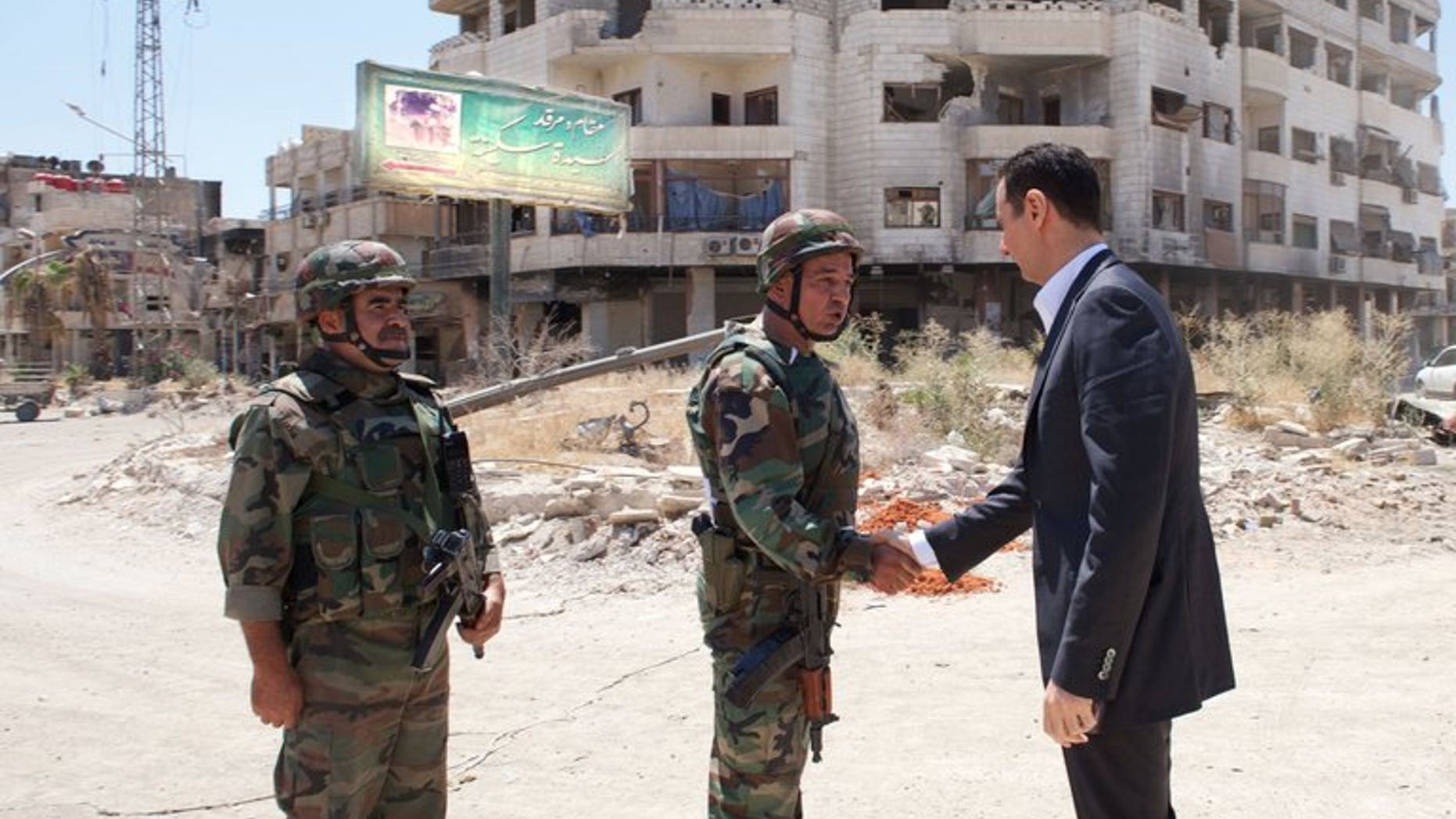 A handout picture released by the Syrian Arab News Agency (SANA) on August 1, 2013 allegedly shows Syrian President Bashar al-Assad shaking hands with a soldier in Daraya, southwestern of the capital Damascus.