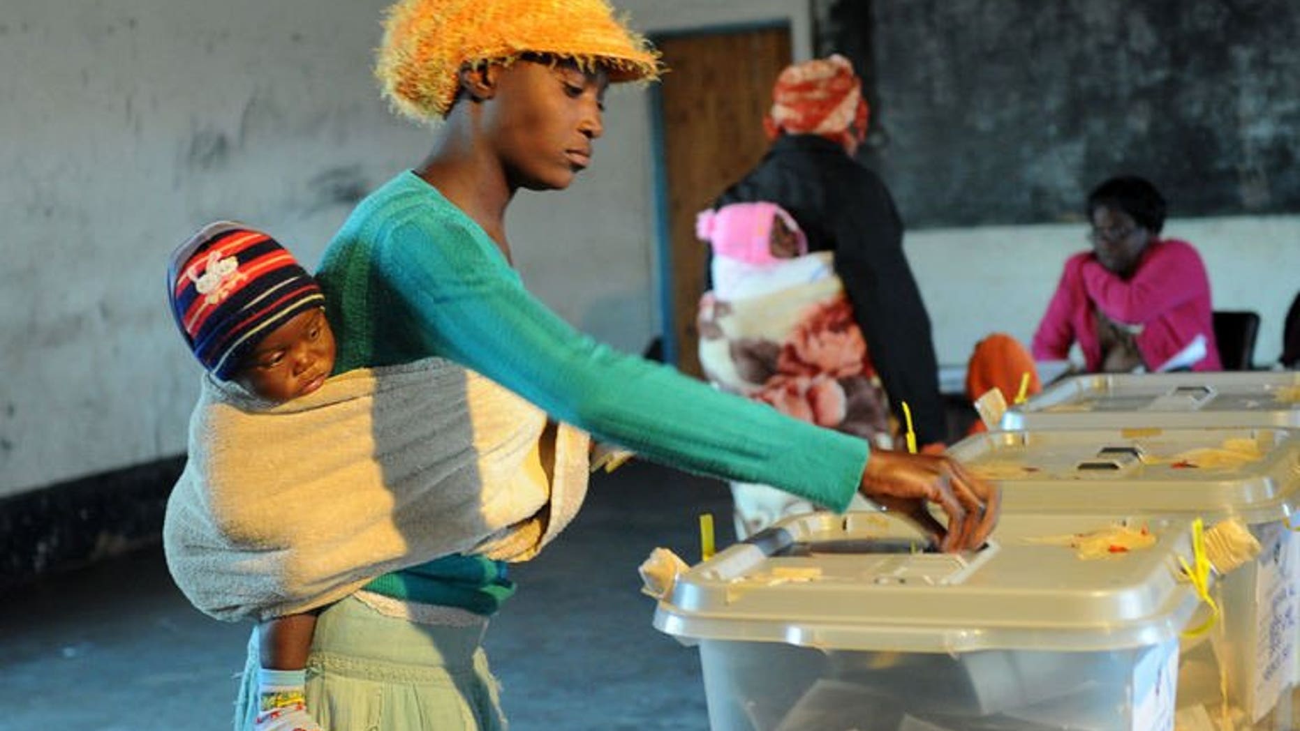 A Zimbabwean mother holding her child casts her ballot at a polling station on July 31, 2013 in Domboshava, 60km north of Harare. The first official results from Zimbabwe's disputed national assembly elections showed President Robert Mugabe's party gaining an early and overwhelming lead Thursday.