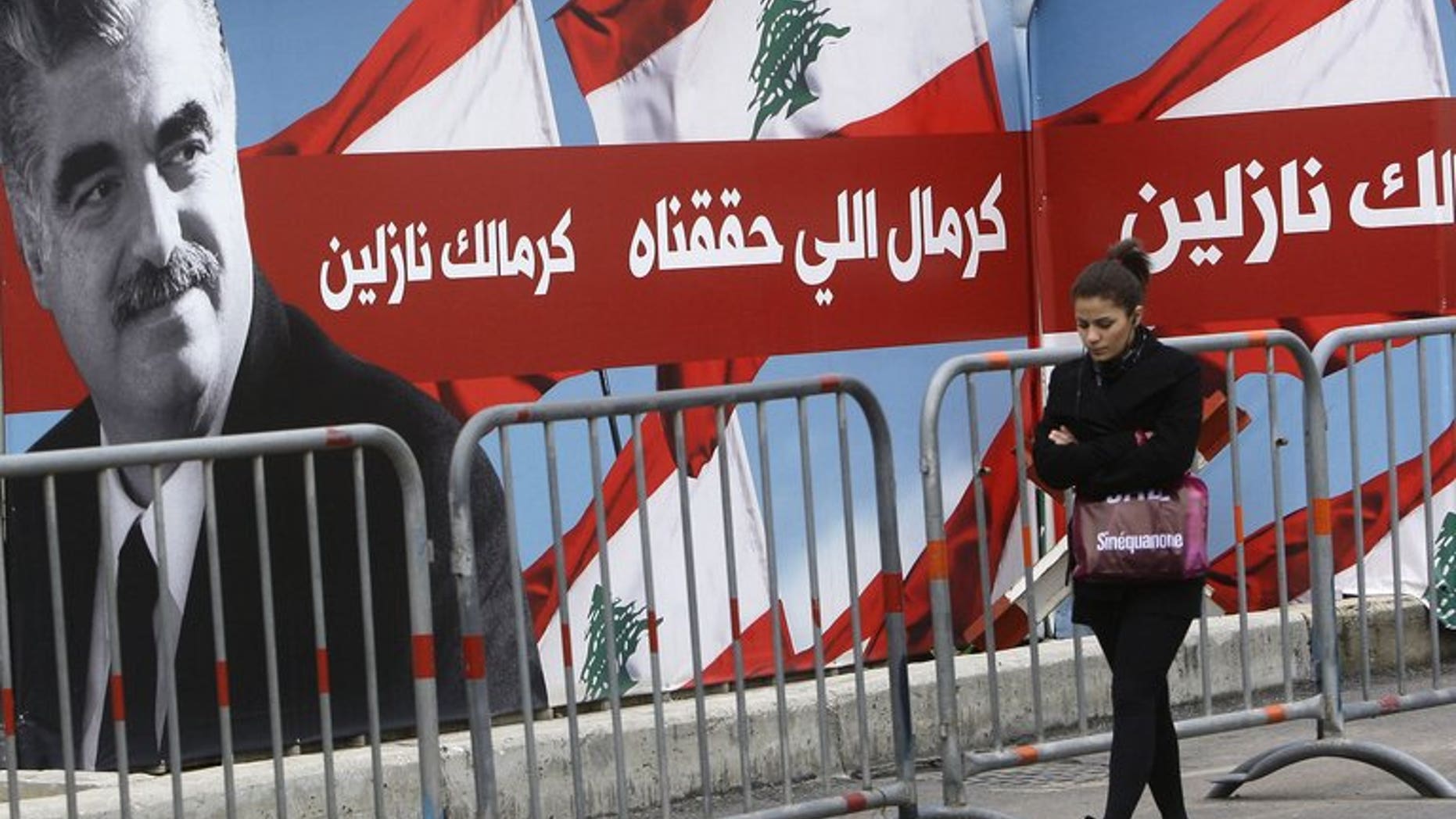 A woman walks past a poster of former Lebanese premier Rafiq Hariri in Beirut, on January 16, 2011. The UN-backed tribunal set up to try the killers of Hariri have set a provisional January start date for the trial.