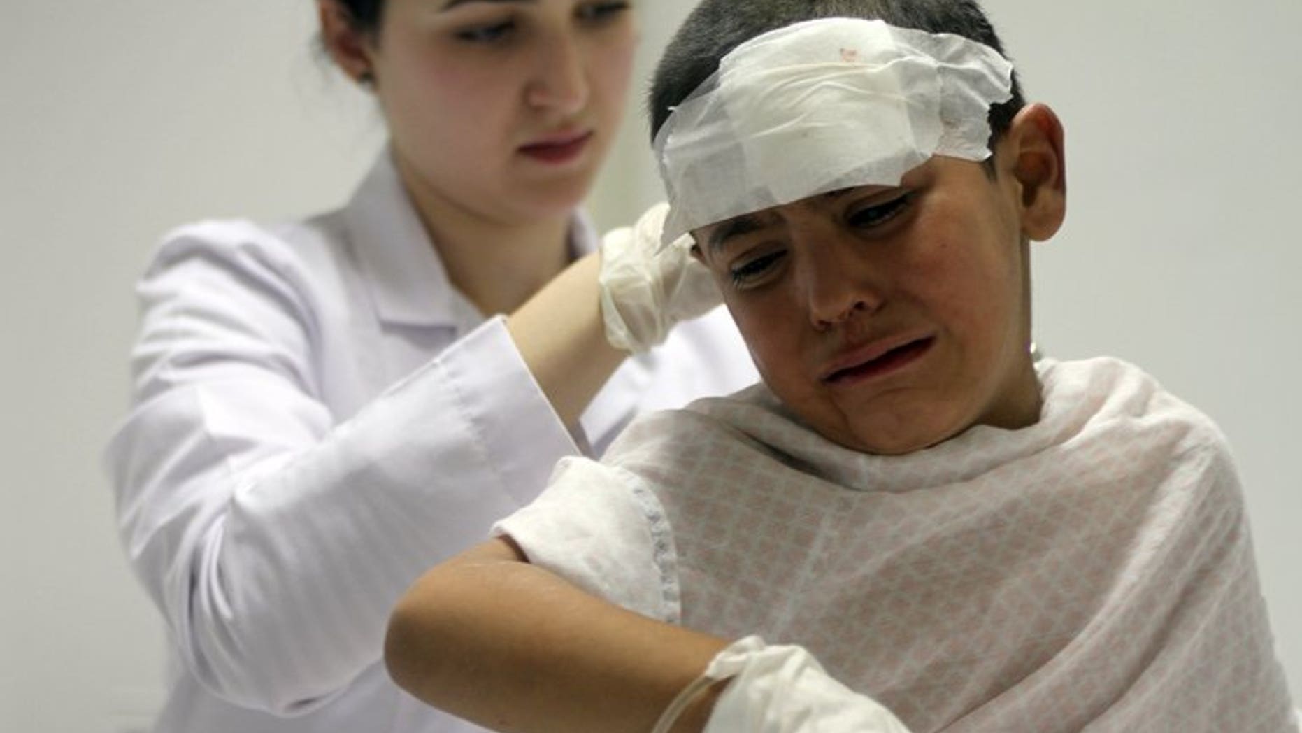 A nurse attends to a wounded boy in the eastern Lebanese city of Baalbek, on August 3, 2013. The bodies of six Syrians killed in an air strike near the border with Lebanon are transported into Baalbek, along with nine injured people, a Lebanese military source tells AFP.