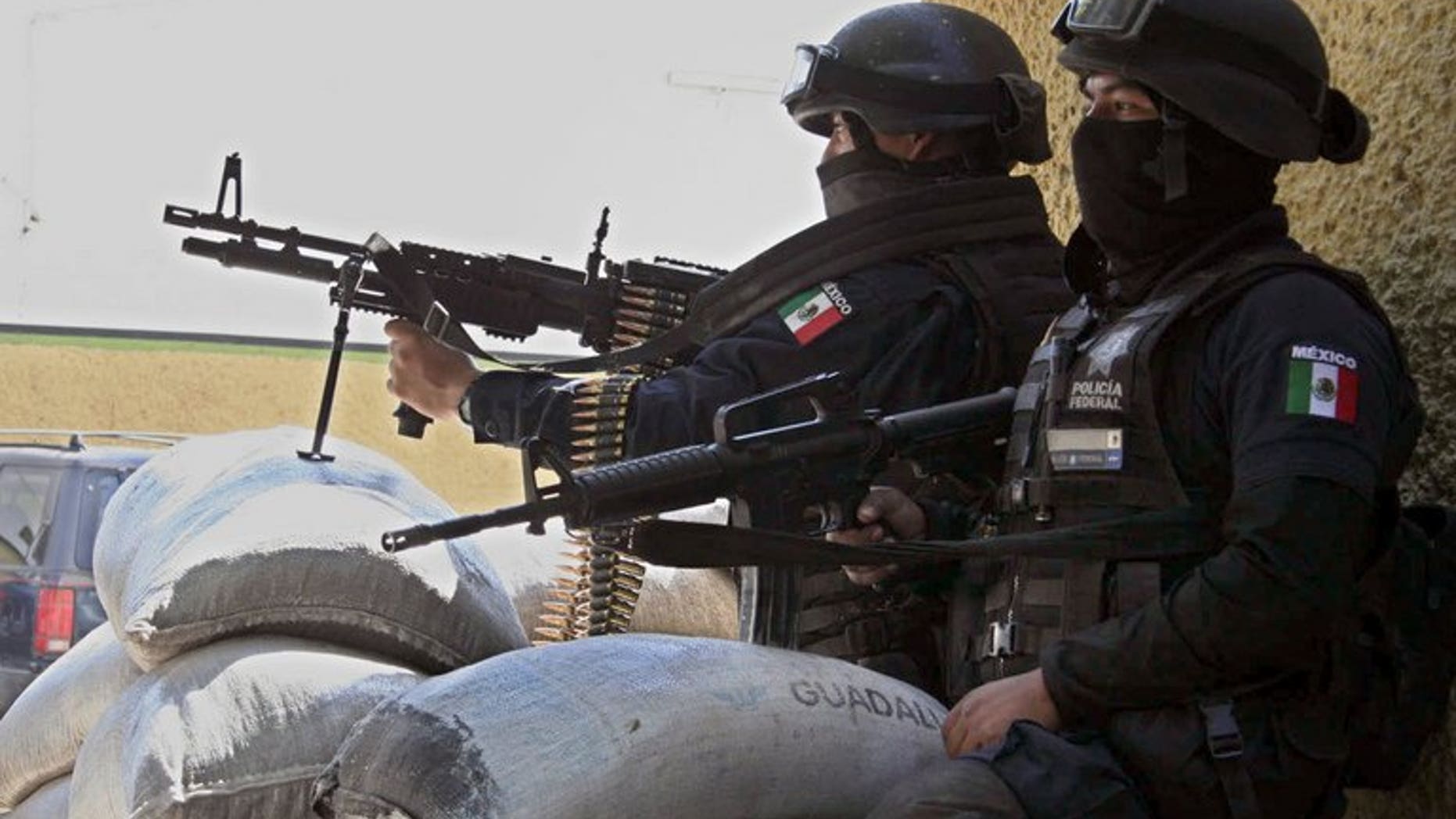 Mexican police take position behind sandbags in Michoacan State on December 10, 2010 after gunmen from La Familia drug cartel drug blocked roads. Three years after drug lord Nazario Moreno was declared dead, doubts abound about his demise, with stories of him indoctrinating recruits every Sunday and hosting a feast last year.