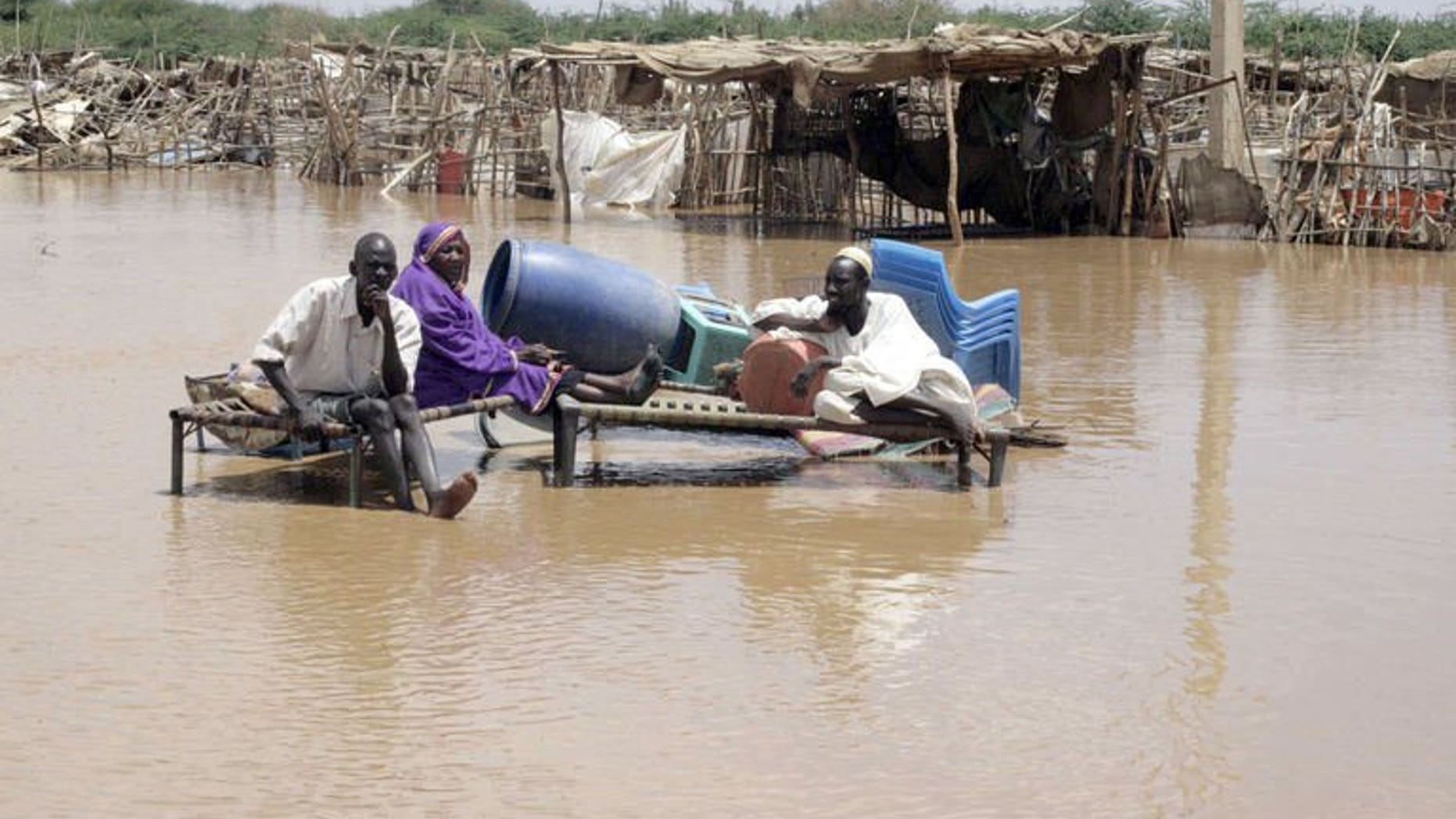 Sudanese men sit on raised sleeping beds with some of their belongings, as flood waters cover a street on August 3, 2013, in Khartoum. Following heavy rains the past few days, there has been flooding throughout the Khartoum area, where drainage is poor.
