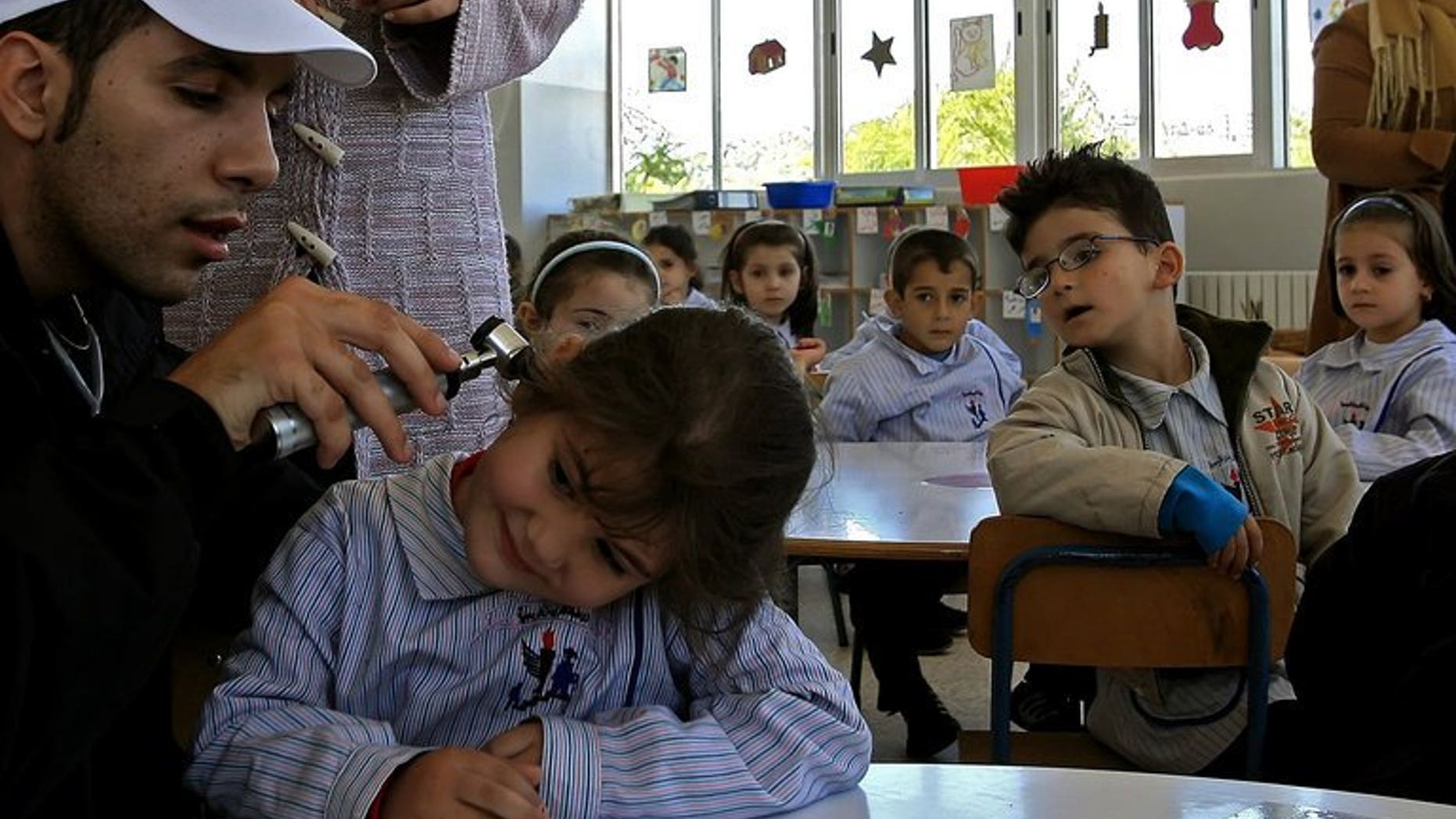 A volunteer checks a student before giving her a polio vaccine in the city of Nabatiyeh, Lebanon on October 31, 2006. Israel on Monday launches a mass campaign in the south of their country to vaccinate 200,000 children up to nine years old against polio, Health Minister Yael German said.