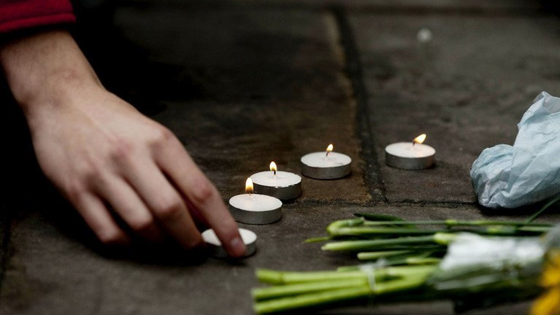 A protester lights a candle at the spot where British newspaper seller Ian Tomlinson died during the G20 demonstrations in London, on April 11, 2009. Metropolitan Police have apologised to Tomlinson's family, who died after being pushed to the ground, and reached an out-of-court setltlement with his family.