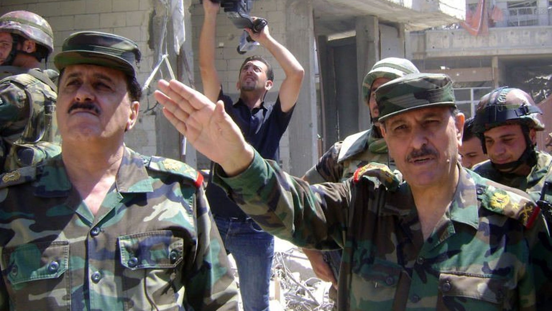Picture released by the Syrian Arab News Agency (SANA) on August 5, 2013 shows Syrian general Fahd al-Freij (R), Defence minister and chief of the armed forces, talking to the media in the district of Khalidiyah in the central Syrian city of Homs. Freij visited army troops in Khaldiyeh, a district the army won back from rebel control in late July, state news agency SANA said on Monday.