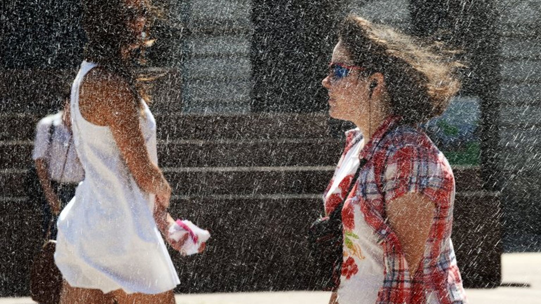 Girls refresh themselves in water spraying from a fire hose as temperatures soar on June 20, 2013 in downtown Warsaw. Thirty-five people have drowned in Poland since the beginning of August, according to police, as Poles attempt to combat a heatwave by flocking to the beach.