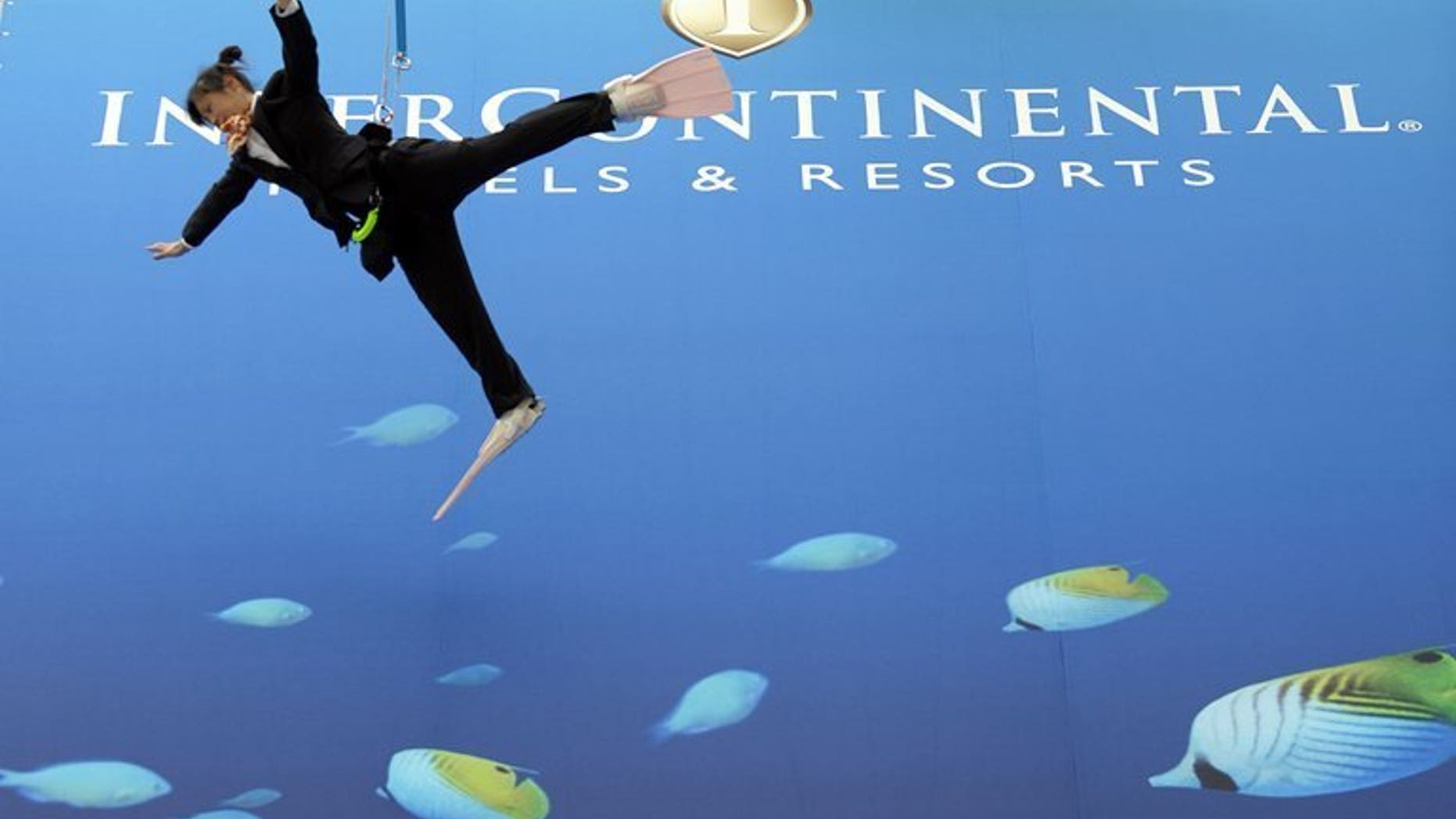 Performers dressed as divers hang off a wall during the opening ceremony for the InterContinental Hotels Group (IHG) hotel in Okinawa, Tokyo, on March 26, 2009. InterContinental Hotels Group on Tuesday announced a 25-percent increase in first-half net profits thanks to a strong showing by its American operations.