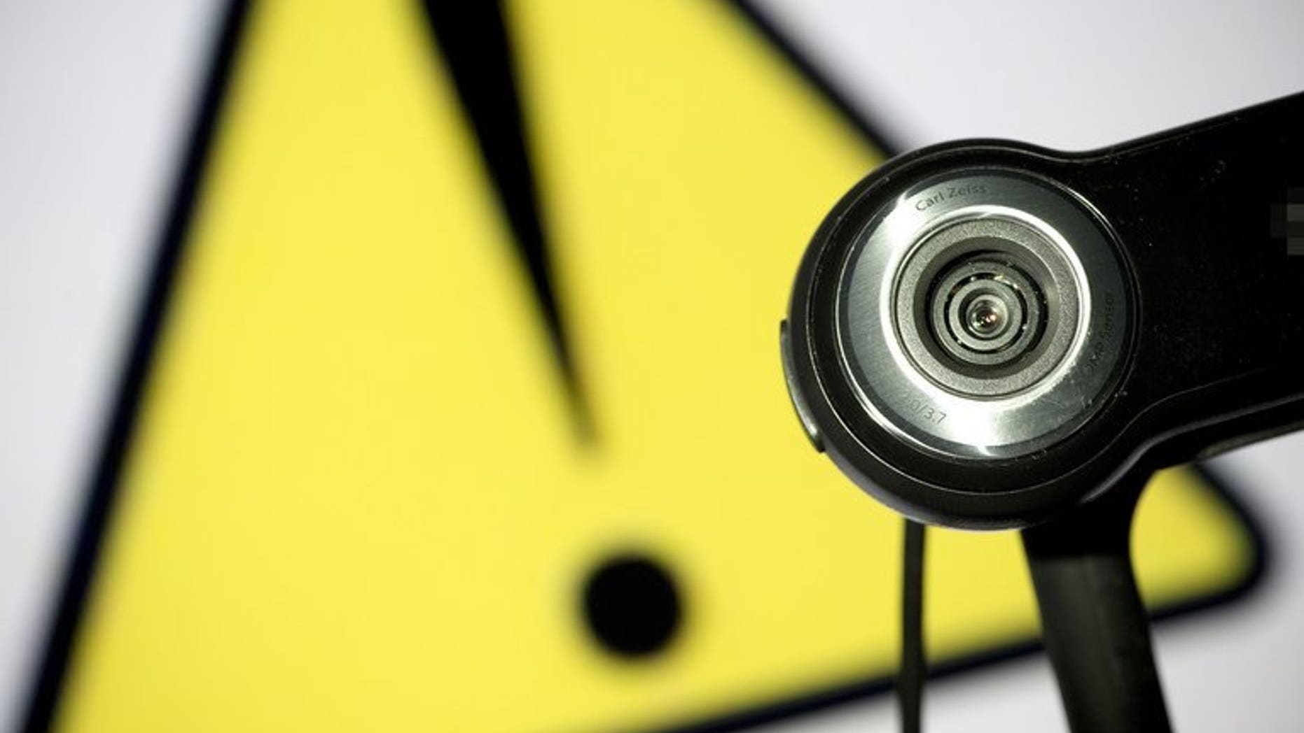 This file illustration photo shows a webcam positioned in front of a danger sign. Two Canadian men were charged Friday in the distribution of child pornography linked to the suicide of a girl who killed herself after months of cyber-bullying, following a sexual assault.