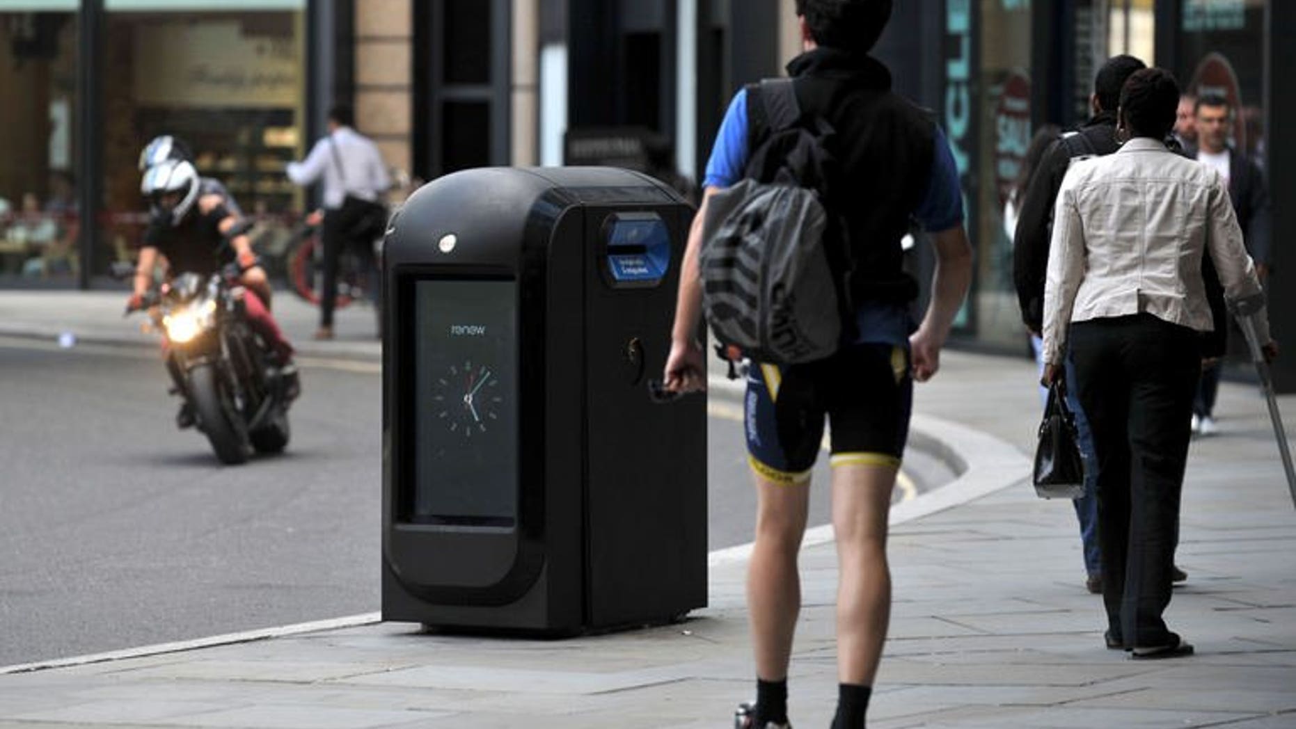 People walk past a "pod" high-tech trash bin in the City of London on August 12, 2013. Authorities in London's financial district ordered Renew, a company using high-tech trash cans to collect smartphone data from passers-by, to cease its activities, and referred the firm to the privacy watchdog.