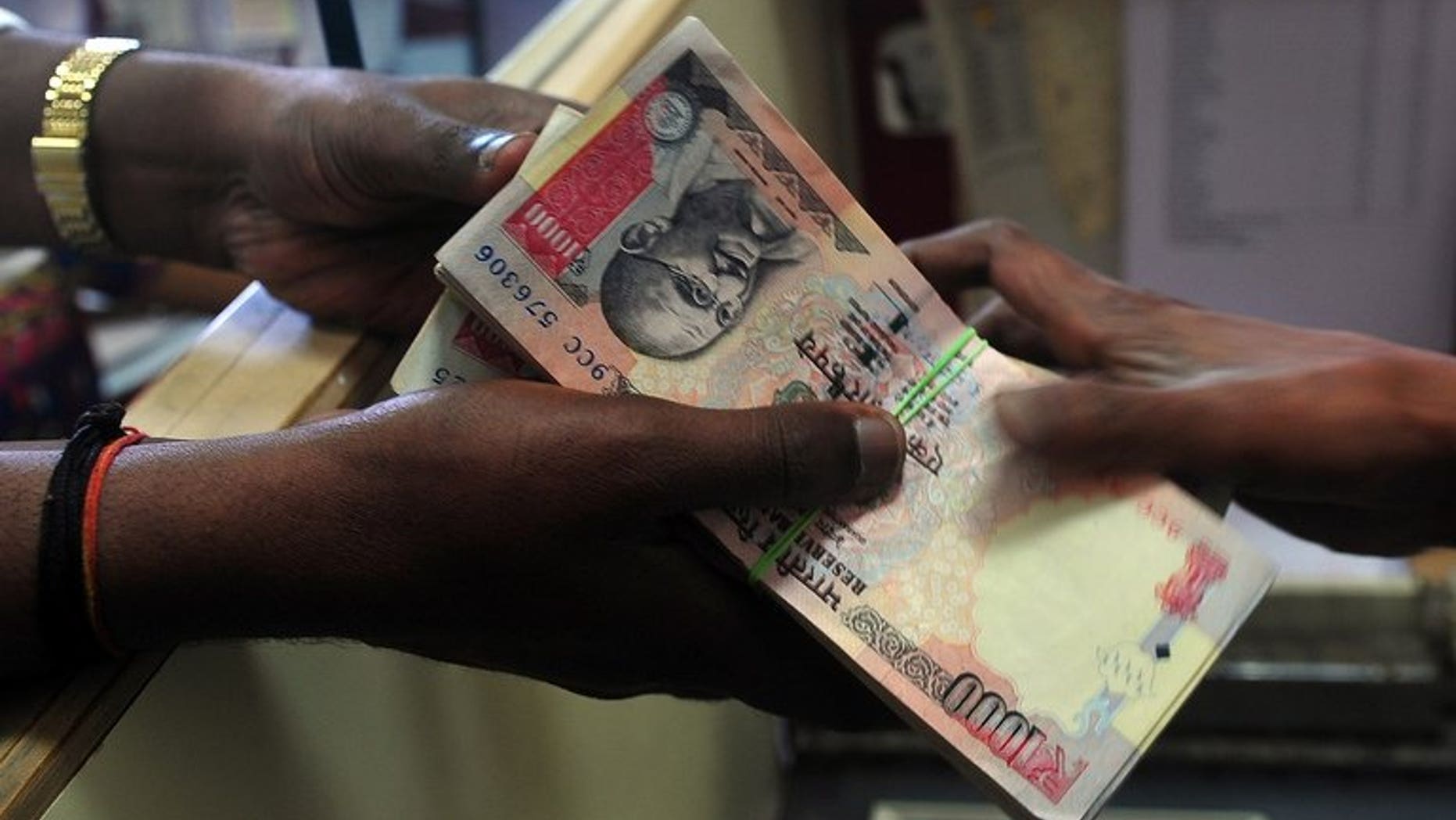 A customer receives a wad of Indian rupee notes from a foreign exchange dealer in Mumbai, on August 6, 2013. The rupee fell in early trade on Tuesday despite the government announcing new measures aimed at narrowing the current account deficit and aiding the ailing local currency.