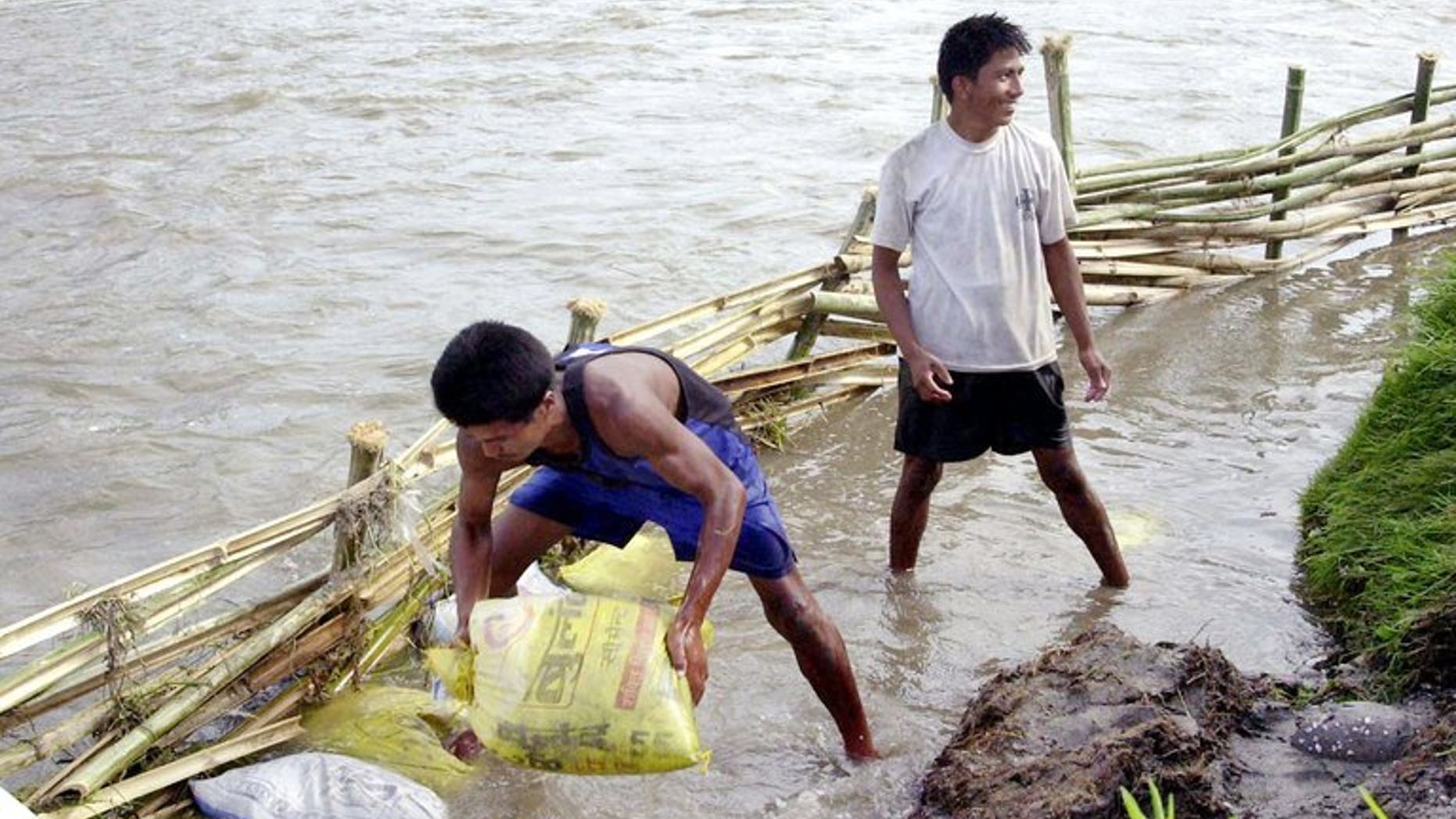 This file photo shows local residents attempting to divert flood waters away from paddy fields near Kathmandu, on June 10, 2003. According to the latest government figures, more than 100 people have been killed in floods and landslides triggered by rains during the monsoon in 2013, which runs from June to September.