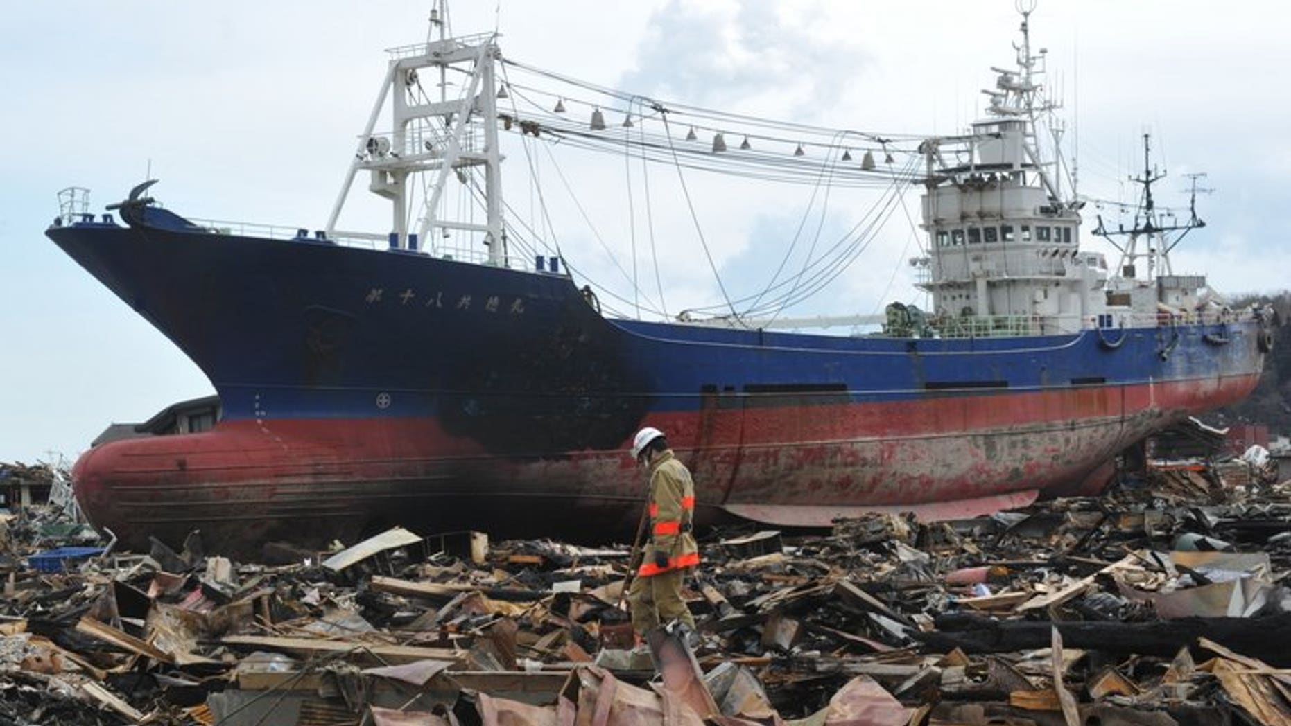 This file photo shows rescuers searching through debris in front of a large grounded ship, in Kesennuma, Miyagi prefecture, on March 17, 2011. The fishing boat that became one of the most poignant symbols of the tsunami disaster is to be scrapped, authorities announced on Tuesday.