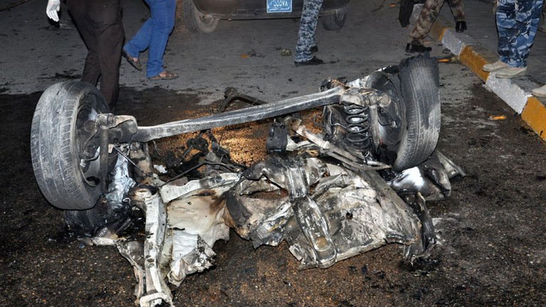 Iraqis inspect the remains of a vehicle at the scene of a car bomb explosion in Nasiriyah, on August 10, 2013. Attacks in Iraq have killed 13 people while militants bombed a major pipeline carrying oil to Turkey.