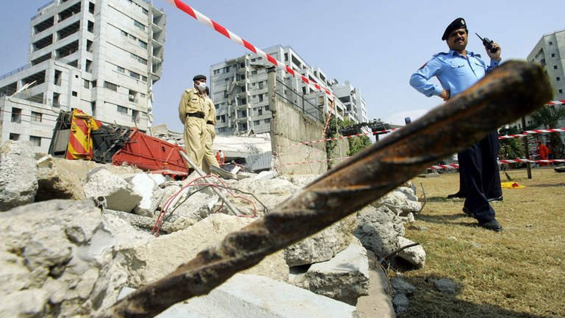 Pakistani police stand guard around the Margalla Towers while rescue workers continue to look for survivors after the building collpased after a powerful earthquake rattled Islamabad, on October 11 2005. A British architect of Pakistani origin -- who is wanted over the 2005 collapse of the Margalla Towers that killed 78 people -- has been arrested in Greece.