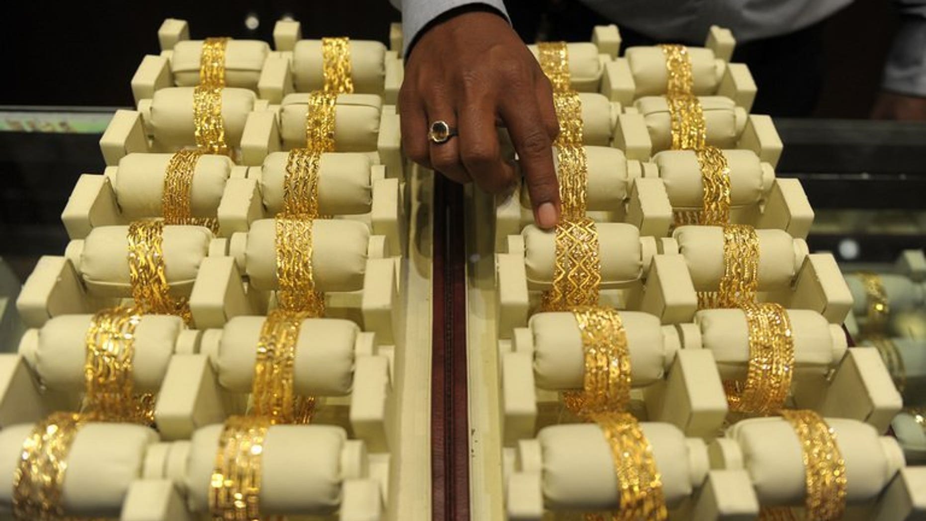 A sales assistant arranges gold bangles for display in a jewellery shop on the Hindu festival Akshaya Tritiya in Hyderabad, southern India on May 13, 2013. India, the world's biggest buyer of gold, raised duties Tuesday on bullion imports for the third time since January as it seeks to narrow the trade gap and defend the rupee.