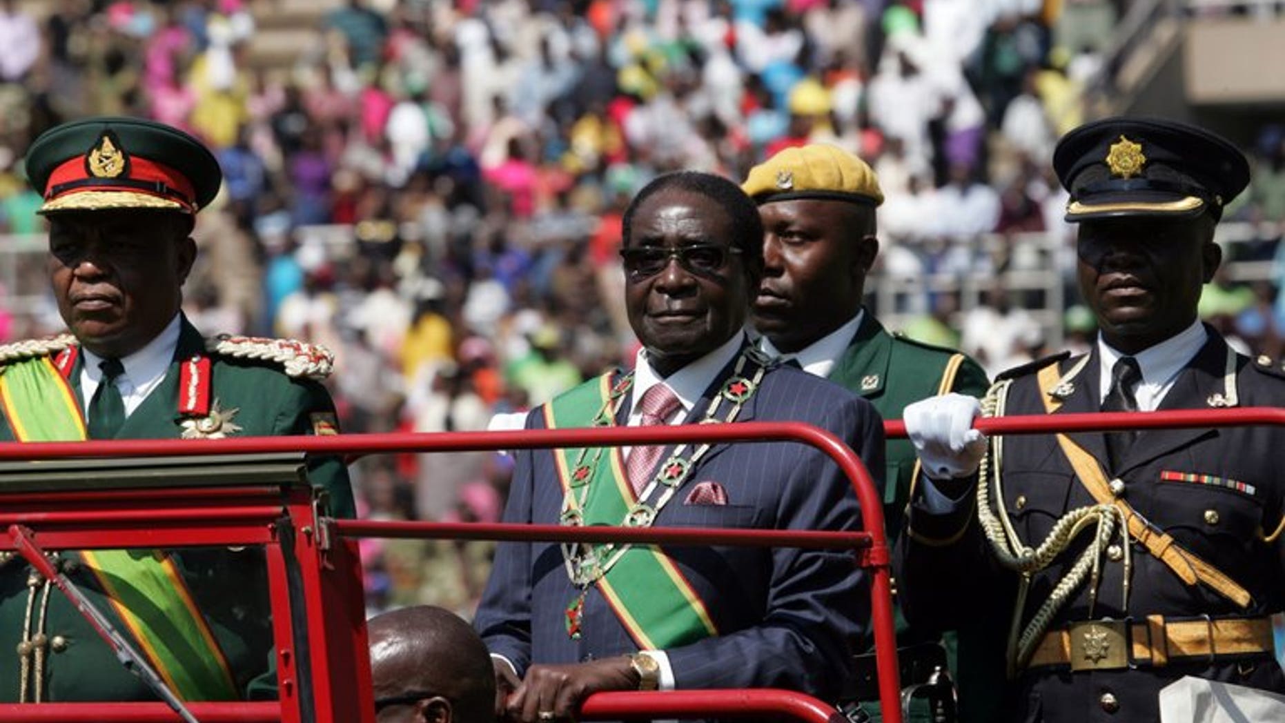 Zimbabwe President Robert Mugabe (centre) inspects a guard of honor in Harare on August 13, 2013. Mugabe vowed to intensify his controversial drive to transfer economic wealth to blacks and scoffed at calls to reform the security services following his disputed re-election.