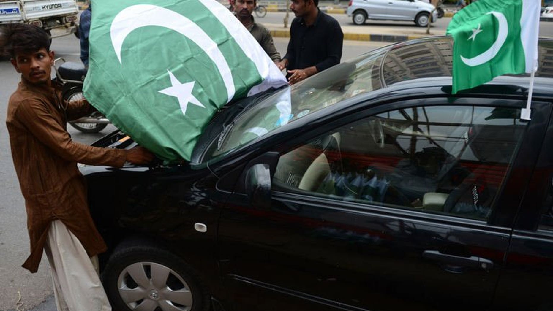 Pakistani vendors decorate a car with national flags ahead of the country's Independence Day in Karachi on August 12, 2013. Twin hand grenade attacks killed at least two people and wounded 28 others belonging to a Shiite Muslim community in Pakistan's port city of Karachi on Tuesday, officials said.