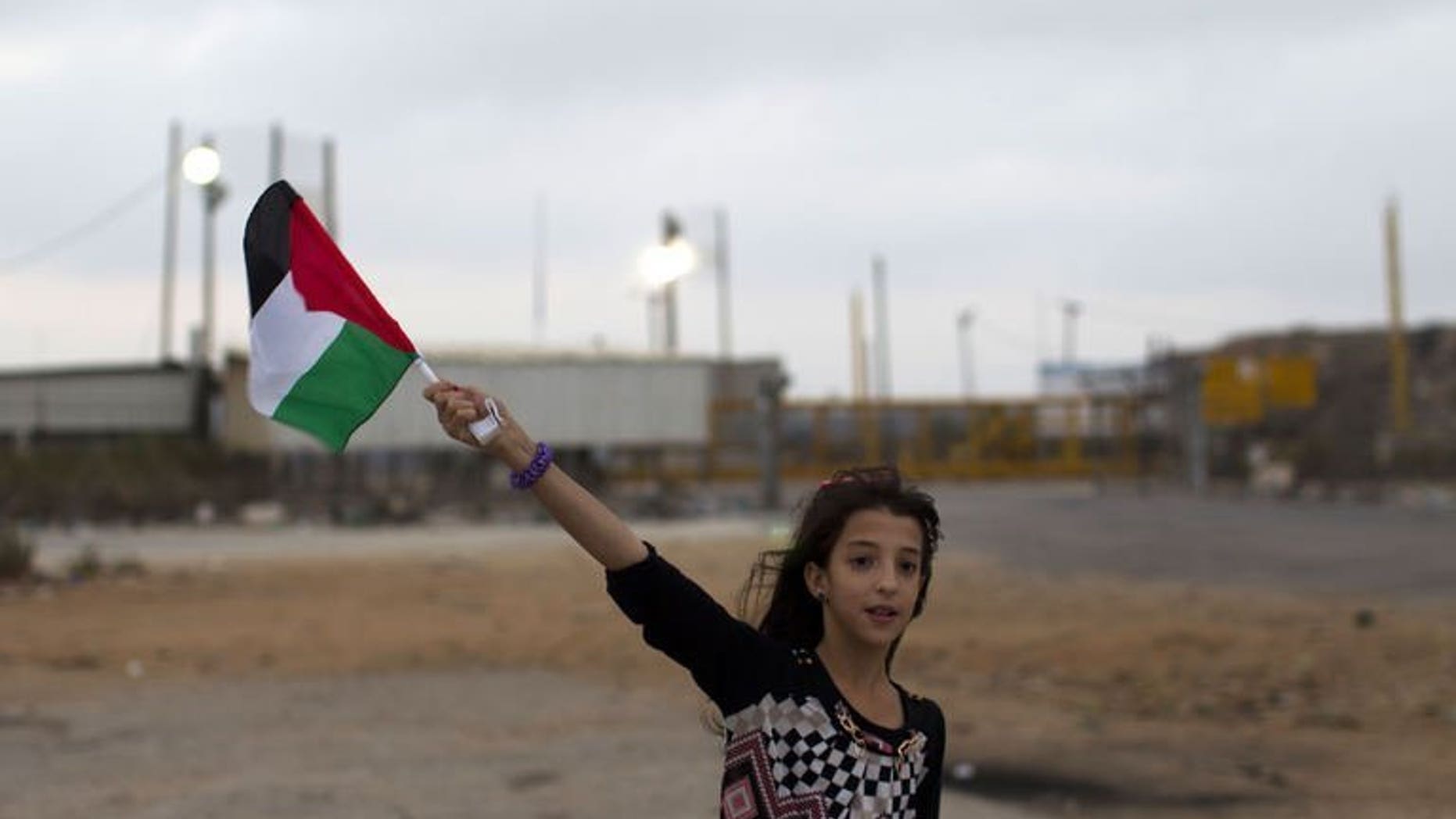 A Palestinian girl from the Israeli occupied West Bank waves the national flag close to the Israeli military prison of Ofer, in the village of Betunia, waiting for the release of Palestinian prisoners on August 13, 2013. An Israeli operation to free 26 Palestinian prisoners got under way late on Tuesday when two busloads of detainees left a jail near Tel Aviv.