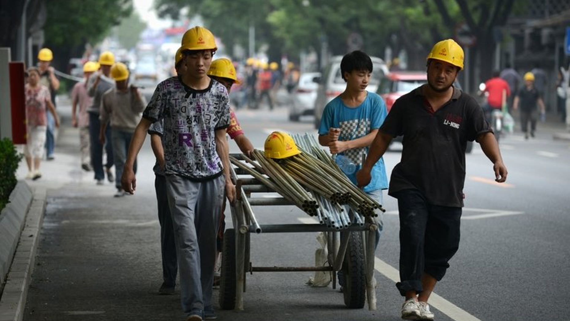 Chinese workers pull steel tubes near a construction site in Beijing on July 11, 2013. Tracking the flows of China's 263 million migrant workers is a huge challenge, but officials have found the answer in packs of pickled root vegetables.