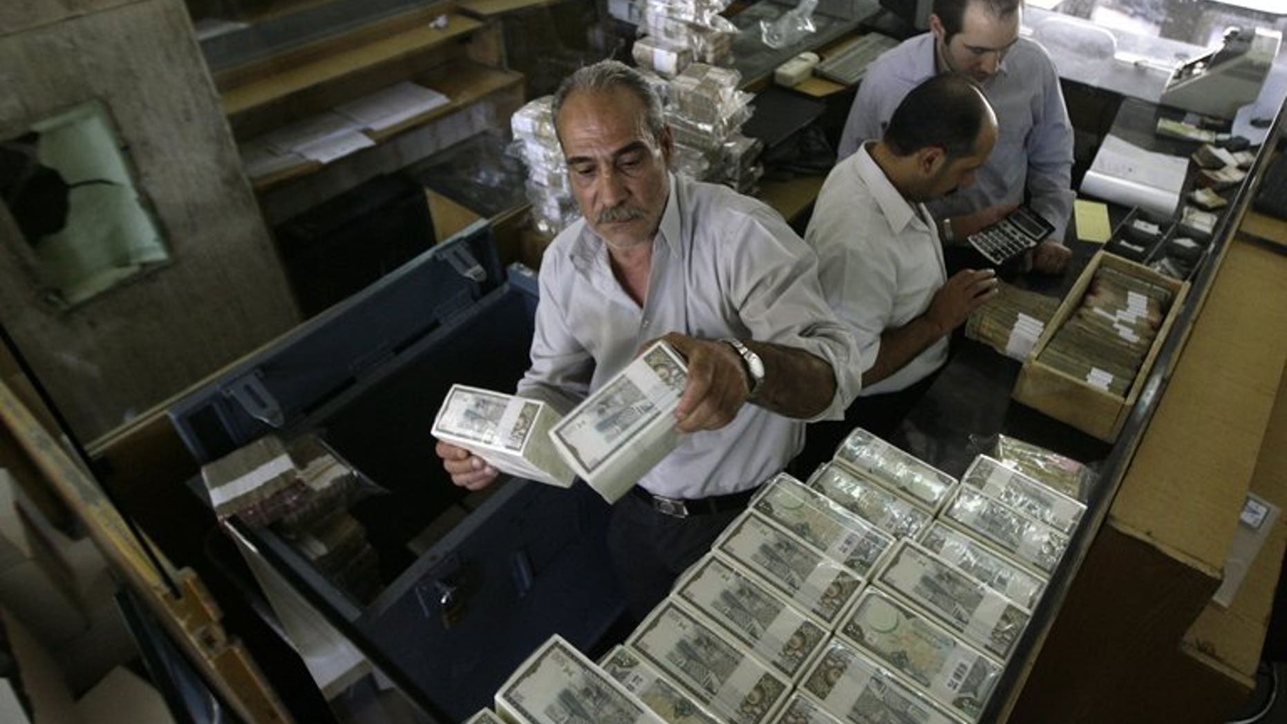 An employee stacks Syrian banknotes at the Syrian Central Bank in Damscus, on August 25, 2011. The central bank in war-torn Syria has lifted restrictions on the sale of dollars to individuals, in a bid to curb black market trade.