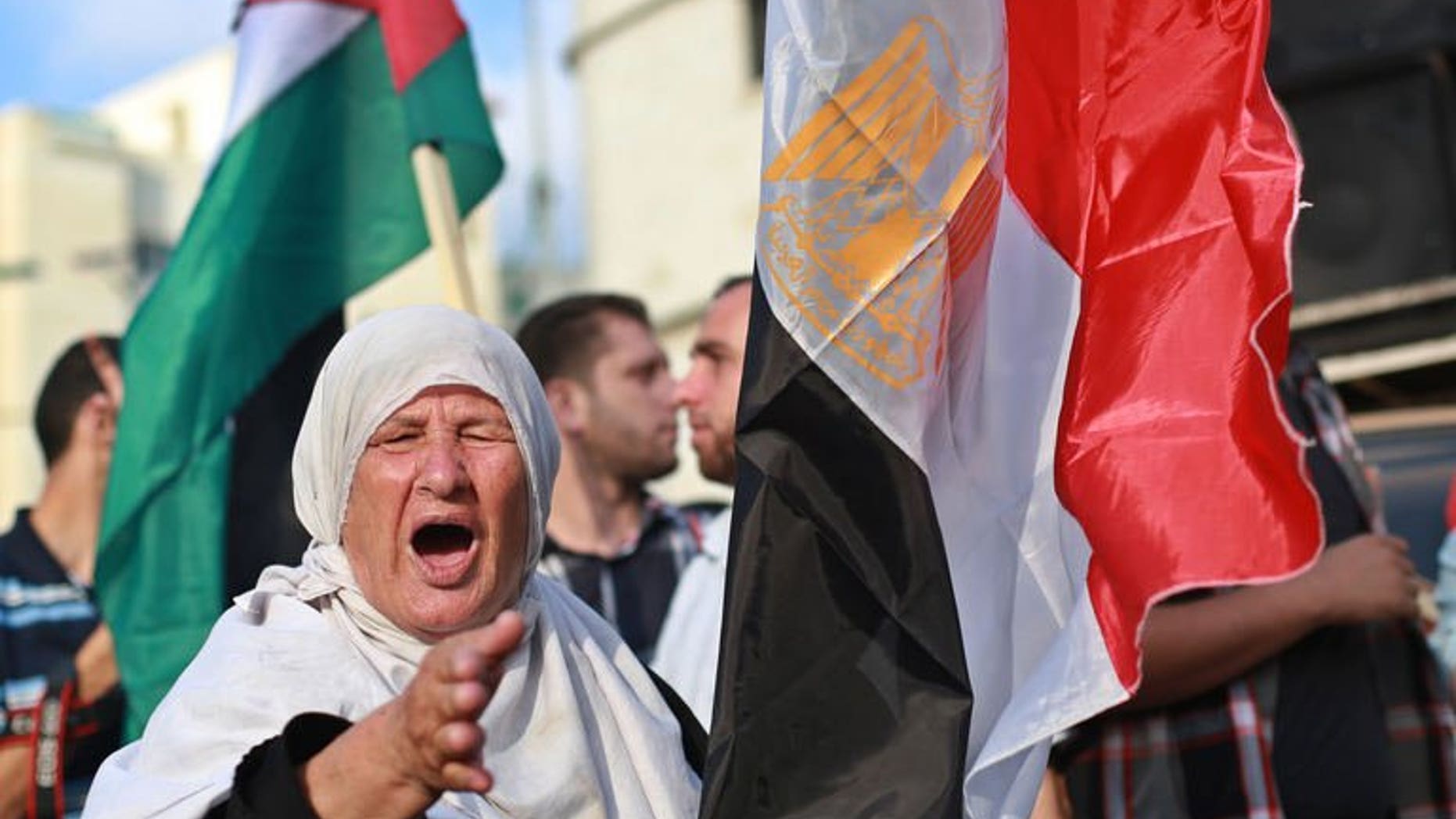 A Palestinian supporter of ousted Egyptian president Mohamed Morsi, shouts slogans as she stands in between the Egyptian (R) and Palestinian flags during a protest against the violence in the Egyptian capital on August 14, 2013, in Gaza City. The Palestinian Islamist movement Hamas condemned Egypt's bloody crackdown on supporters of ousted president Mohammed Morsi as a "terrible massacre."