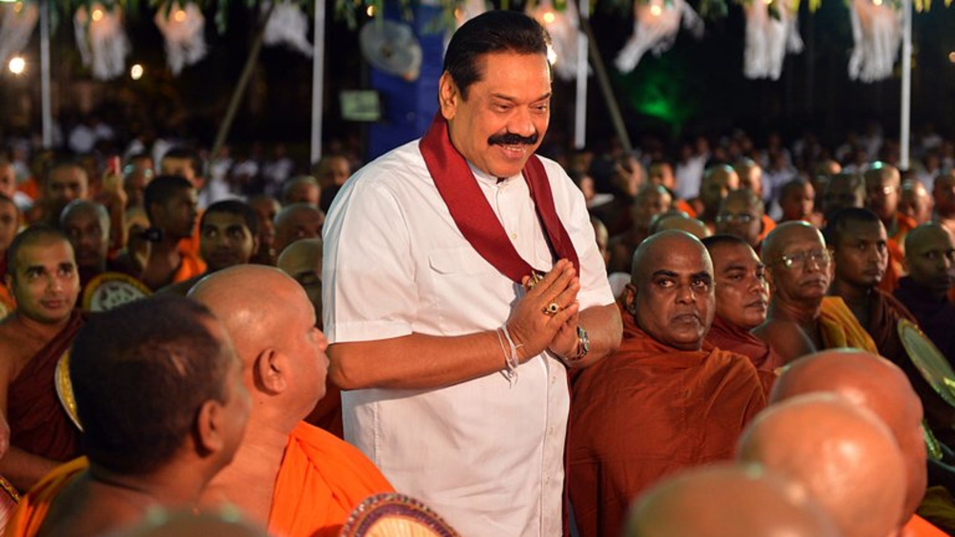 Sri Lankan President Mahinda Rajapakse (C) walks past Buddhist monks during the War Heroes religious ceremony in Colombo on May 9, 2013. Rajapakse ordered a new investigation into the disappearance of thousands of people in the island's northeast during an ethnic war which ended four years ago.
