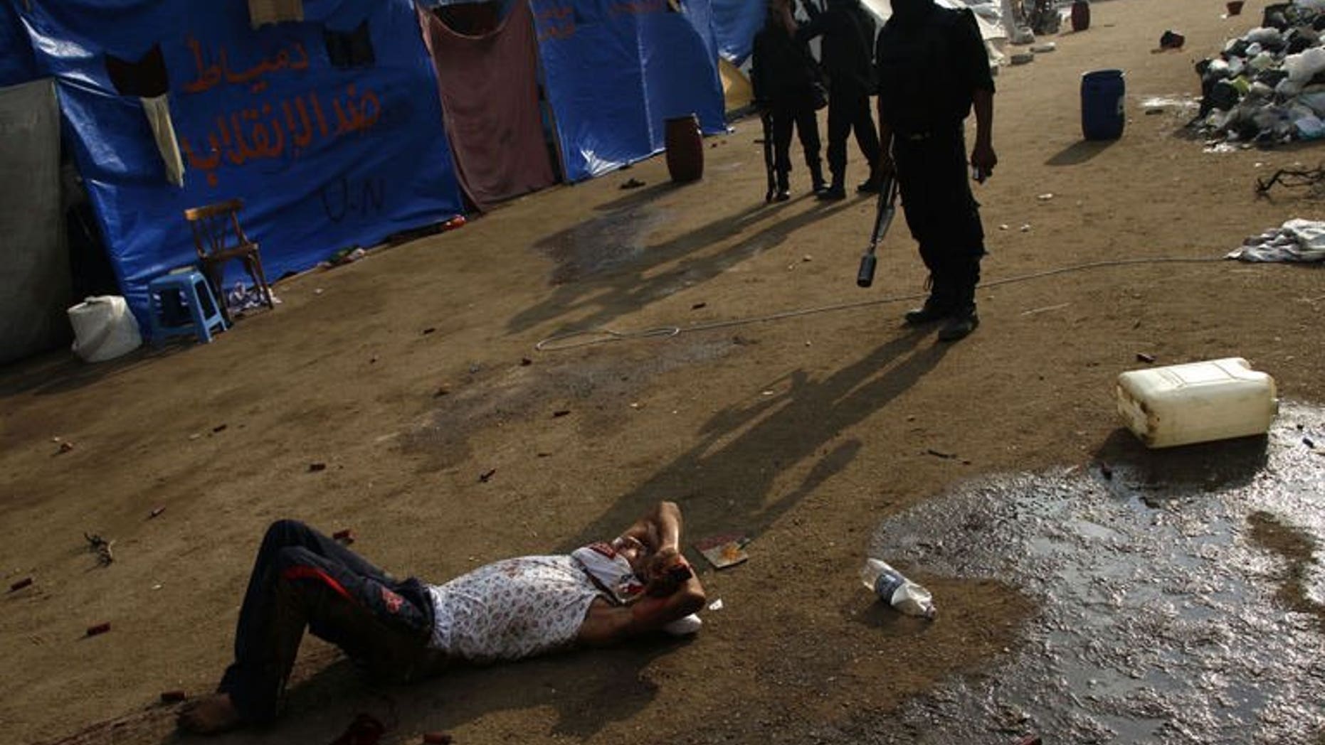 Egyptian riot policemen stand behind a wounded youth during clashes that broke out as Egyptian security forces moved in to disperse supporters of Egypt's deposed president Mohamed Morsi in a huge protest camp near Rabaa al-Adawiya mosque in eastern Cairo on August 14, 2013.