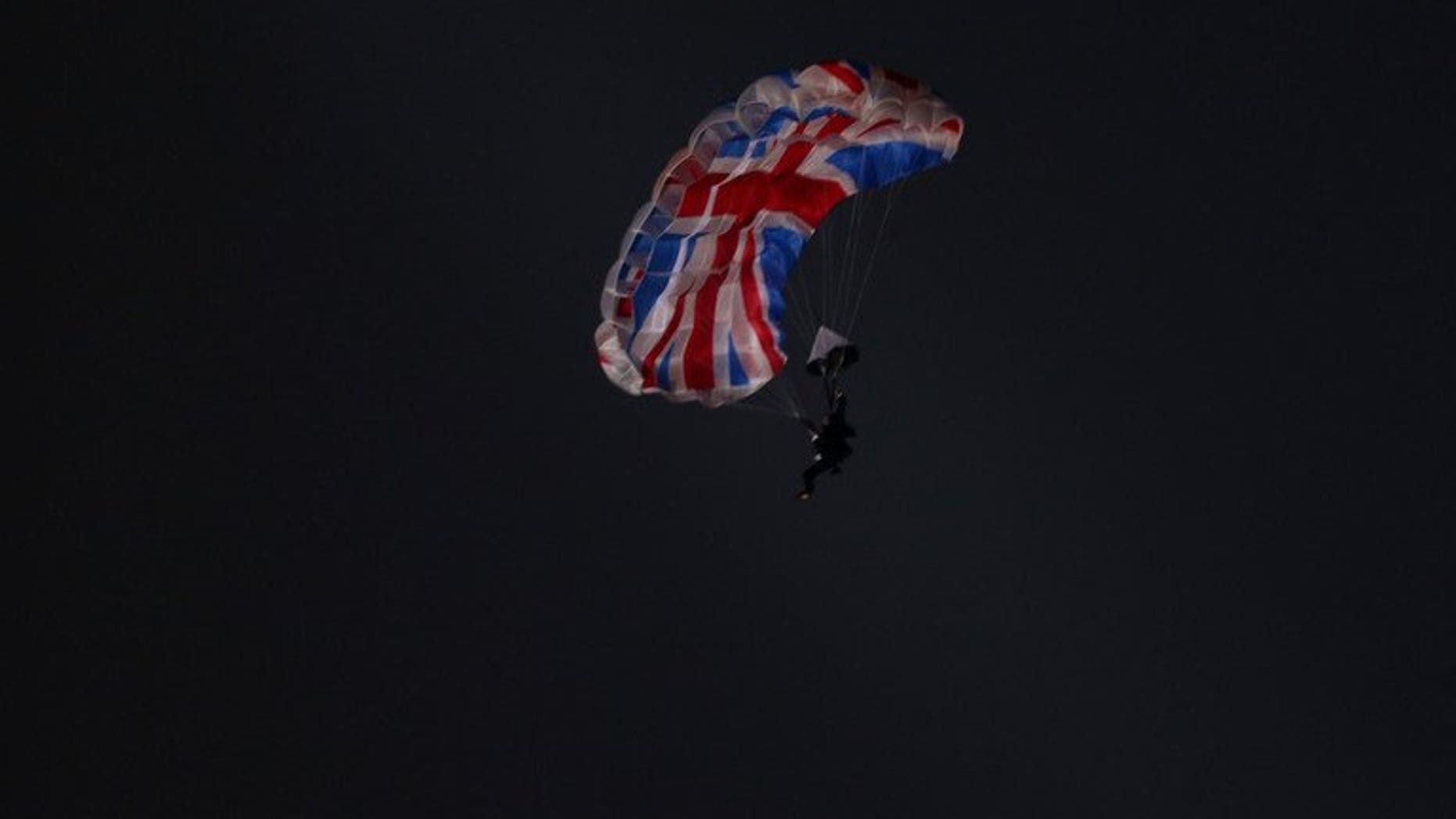 Mark Sutton, a stuntman playing the role of Daniel Craig as James Bond, parachutes out of a helicopter during the London Olympics opening ceremony on July 27, 2012. Sutton has died while wing-diving in Switzerland, British press reported Thursday.