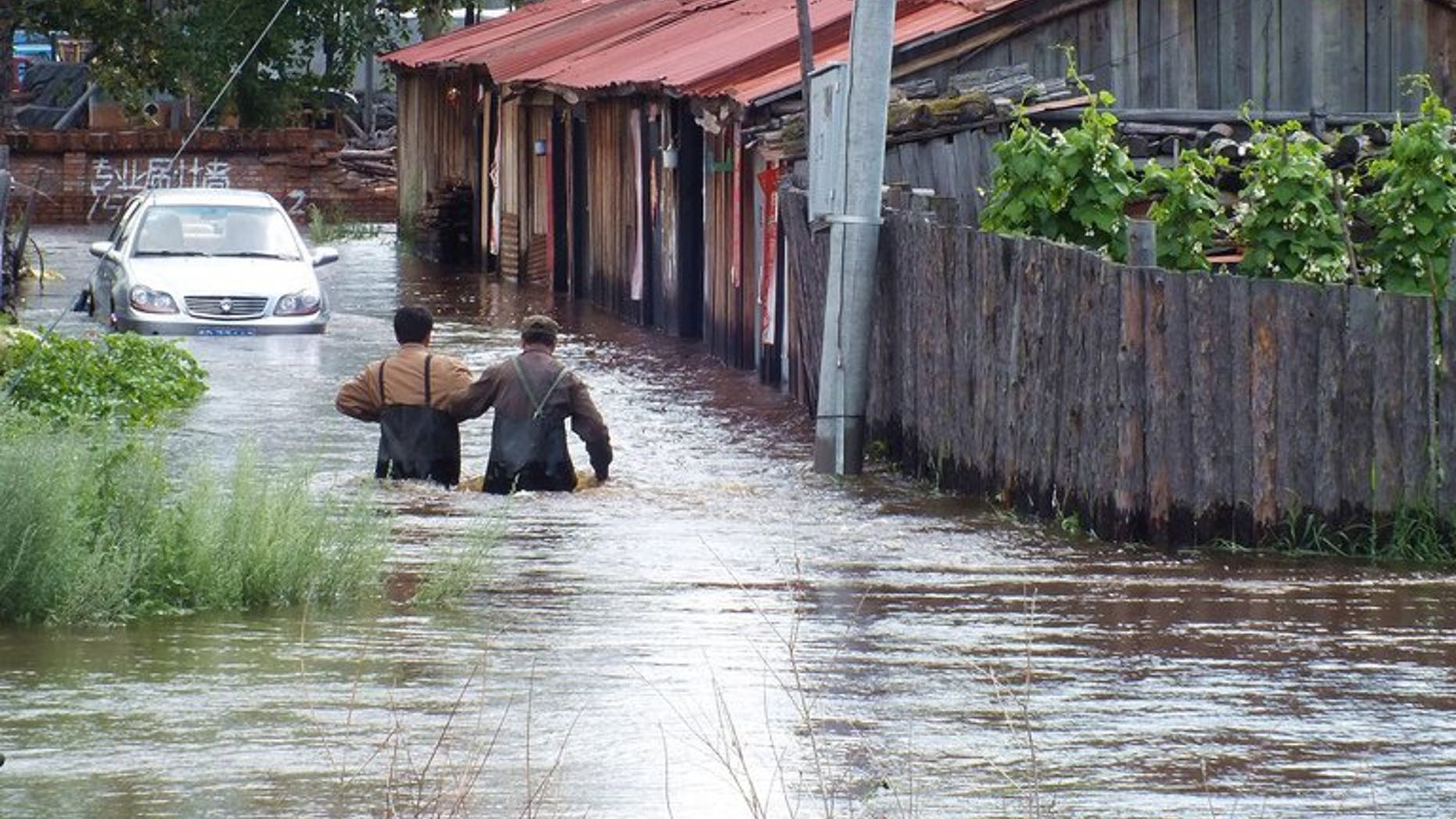 This picture taken on July 25, 2013 shows local residents wading in a flooded area in Yakeshi, in northern China's Inner Mongolia region. Twenty-five people have been killed by floods which hit northeastern China over the past week, state media said Saturday, as other parts of the country continued to experience a heatwave.