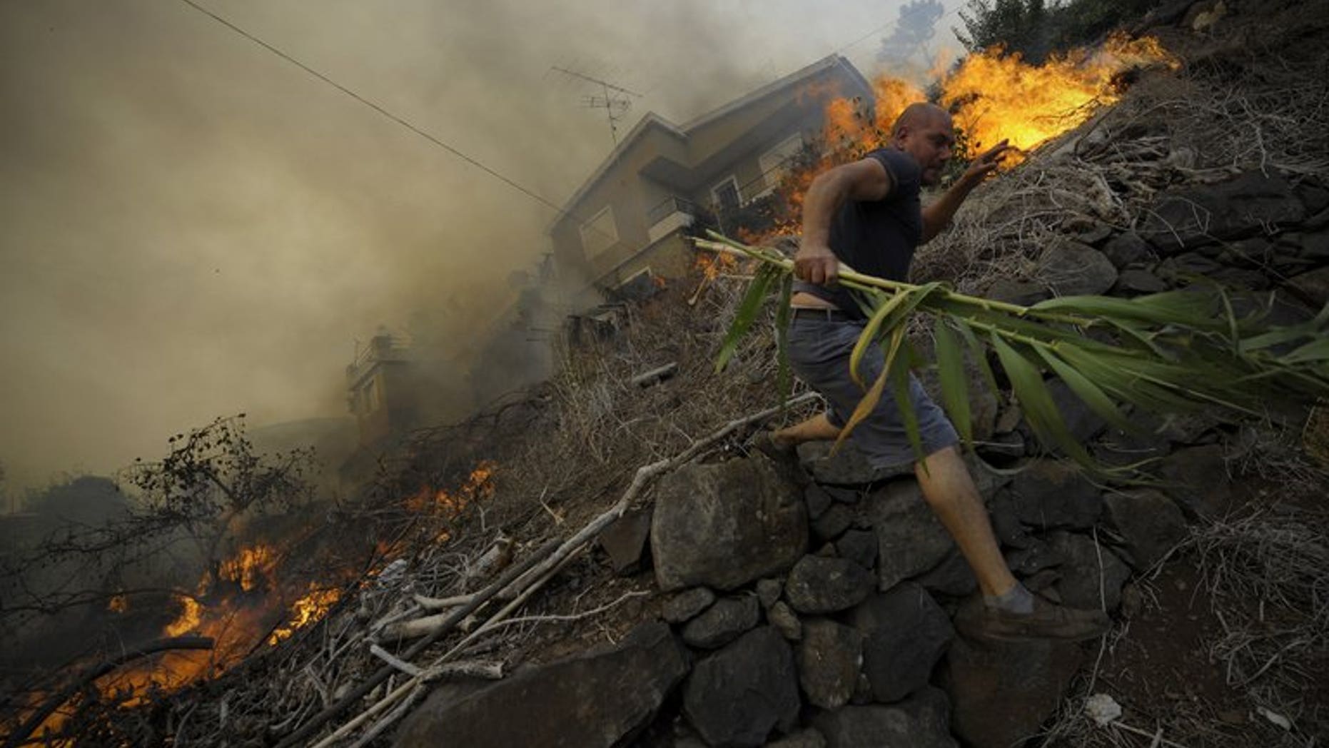 A man runs away from the flames as a wildfire rages near houses in Assomada, Madeira on July 21, 2012. A raging wildfire has prompted the evacuation of a hospital outside Funchal, capital of the Portuguese island of Madeira, officials said Saturday.