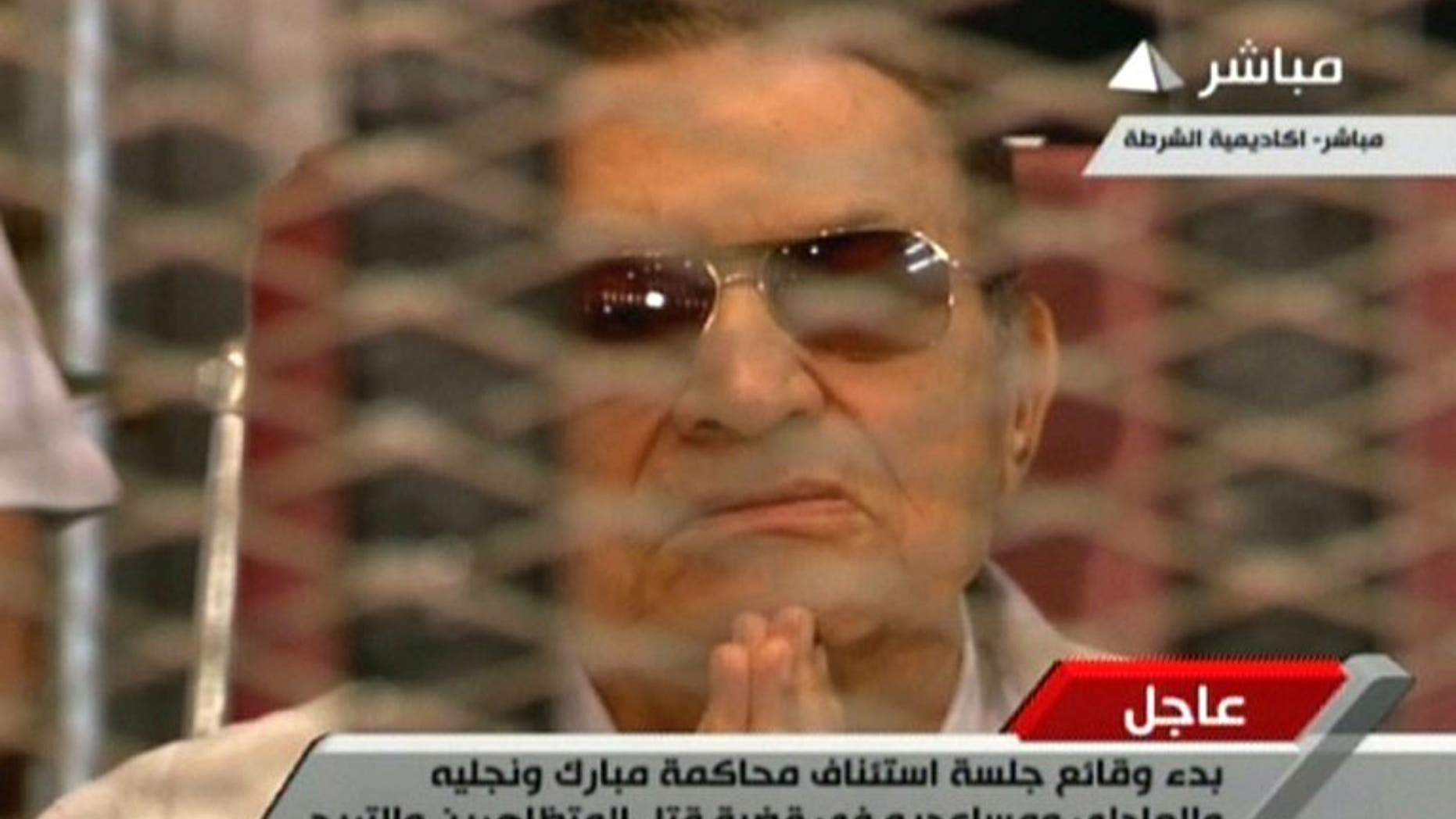 An image grab taken from Egyptian state TV shows ousted Egyptian president Hosni Mubarak gesturing behind bars during a hearing in his retrial at the police academy in Cairo on July 6, 2013. The trial of former Egyptian president Hosni Mubarak on charges of complicity in the deaths of protesters was adjourned on Saturday until August 25, after a brief session.