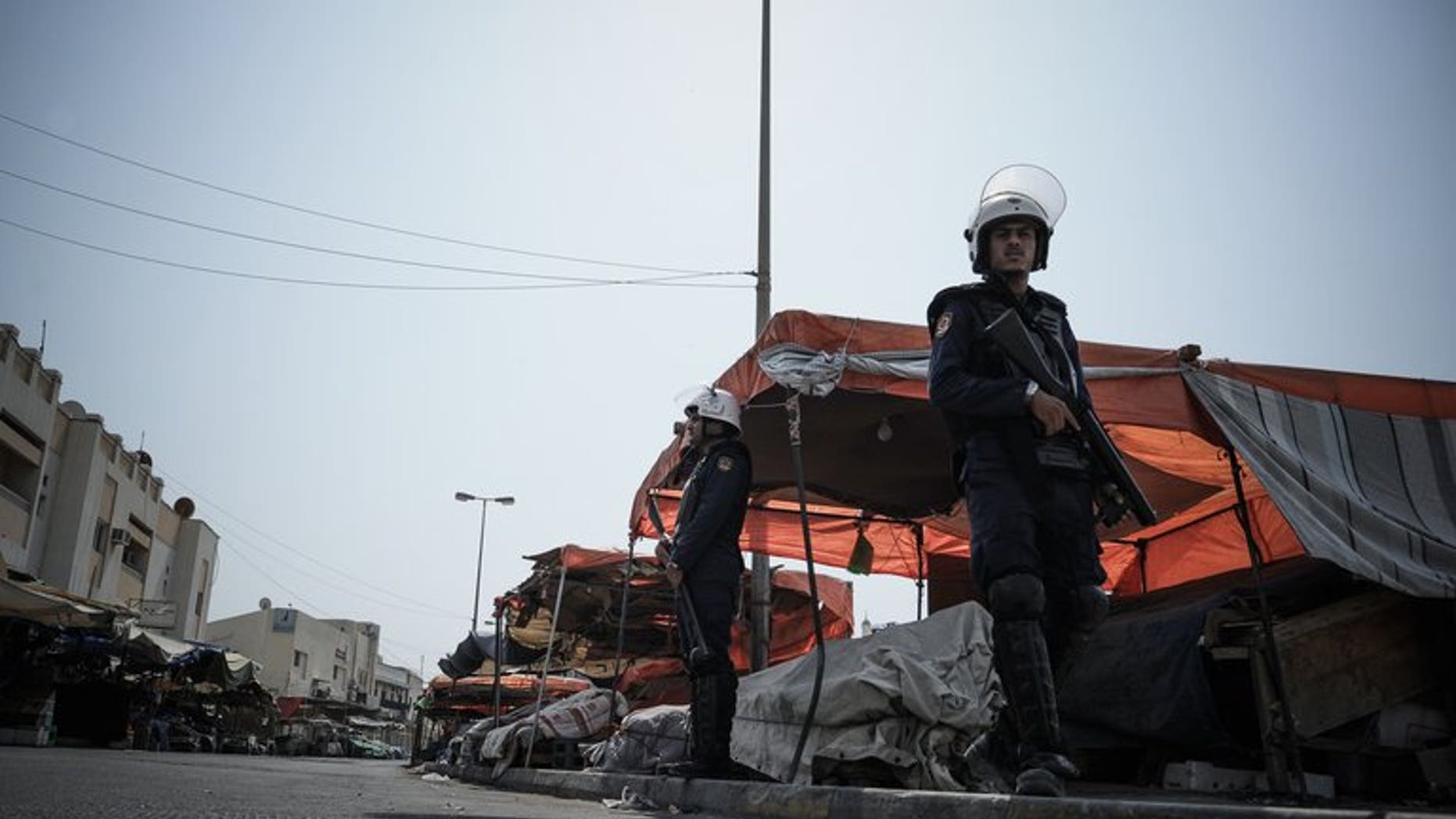 Bahraini police force officers on guard watching the road that runs through the market in the village of Jidd Hafs, west of Manama, on August 14, 2013. Bahrain's prosecutor has said it has launched a probe into riots at a detention centre as an activist said 40 prisoners were wounded as authorities restored order.