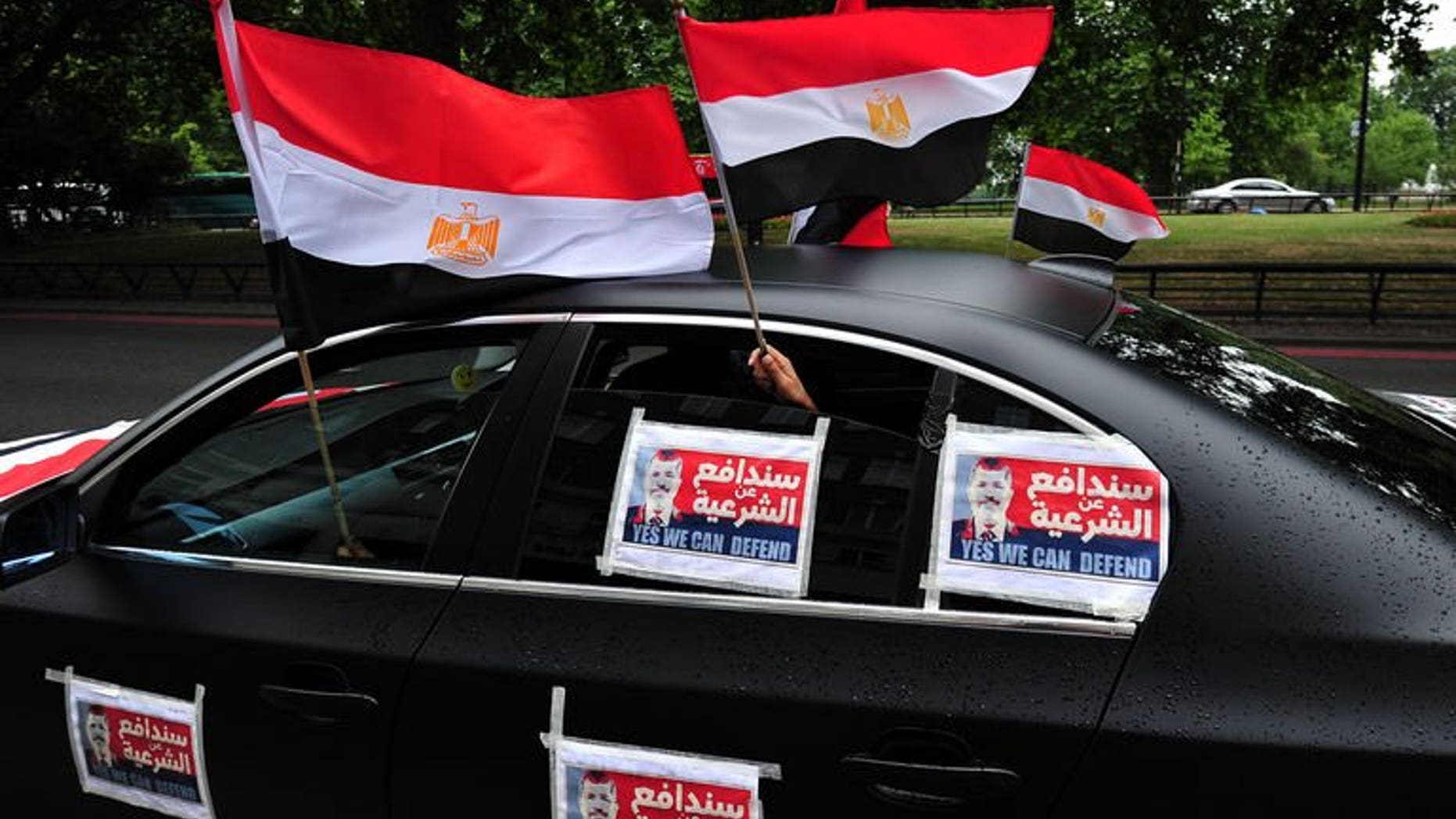 Demonstrators supporting Egypt's ousted Islamist president Mohamed Morsi hold Egyptian flags (L) from a car plastered with Morsi posters during a rally against the crackdown on protesters in Egypt in central London on August 17, 2013.