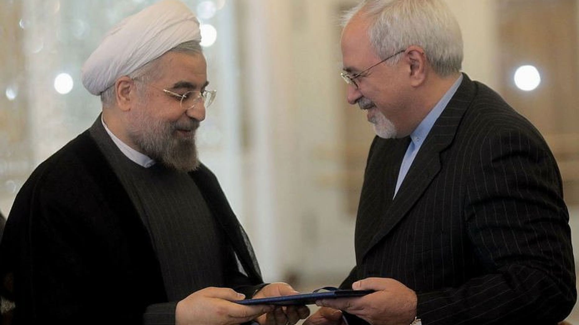 This picture, released by the Iranian president's official website, shows Iranian President Hassan Rowhani (L) handing over the decree to Foreign Minister Mohammad Javad Zarif at the Foreign Ministry in Tehran on August 17, 2013. The EU's top diplomat Catherine Ashton, who leads global talks with Tehran on its nuclear drive, called for a resumption of the talks in a phone conversation with Zarif.