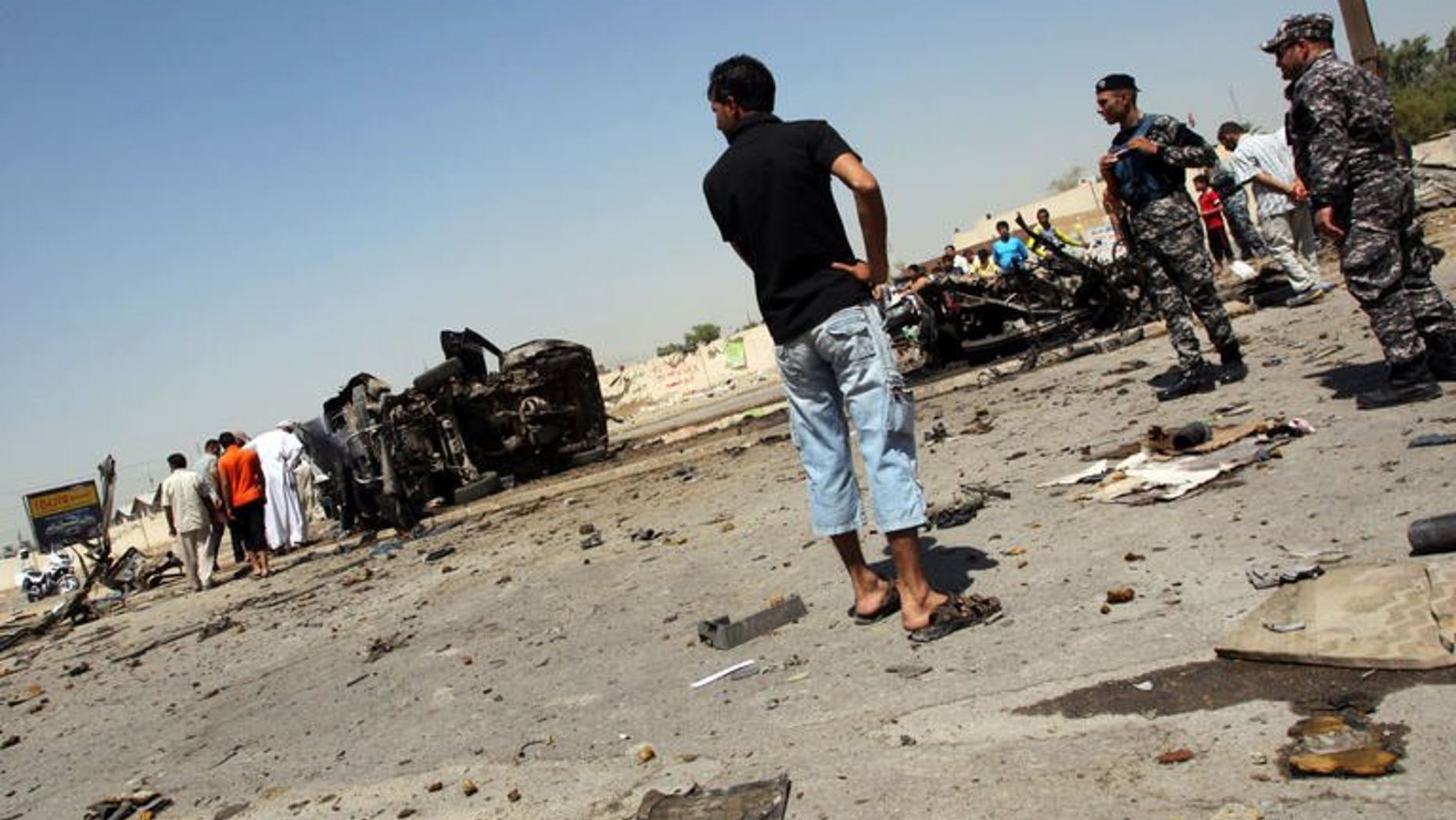 Iraqis and security forces inspect the scene of a car bomb attack near the office of Al-Ahad television channel, which is affiliated with a Shiite militant group, in Baghdad's eastern neighbourhood of Baladiyat on August 15, 2013. Attacks in Iraq killed at least six people including a local council member on Sunday, officials said, the latest in a surge of violence plaguing the country.