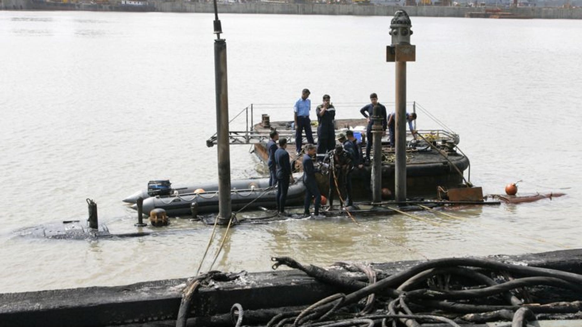 In this handout photograph released by the Ministry of Defence and taken on August 14, 2013, Indian Navy divers are pictured at the conning tower of the stricken INS Sindhurakshak, after the submarine sank following an explosion at the naval dockyard in Mumbai. Divers have recovered another burnt body from a submarine that exploded in Mumbai as they battled to find 12 remaining crewmen.