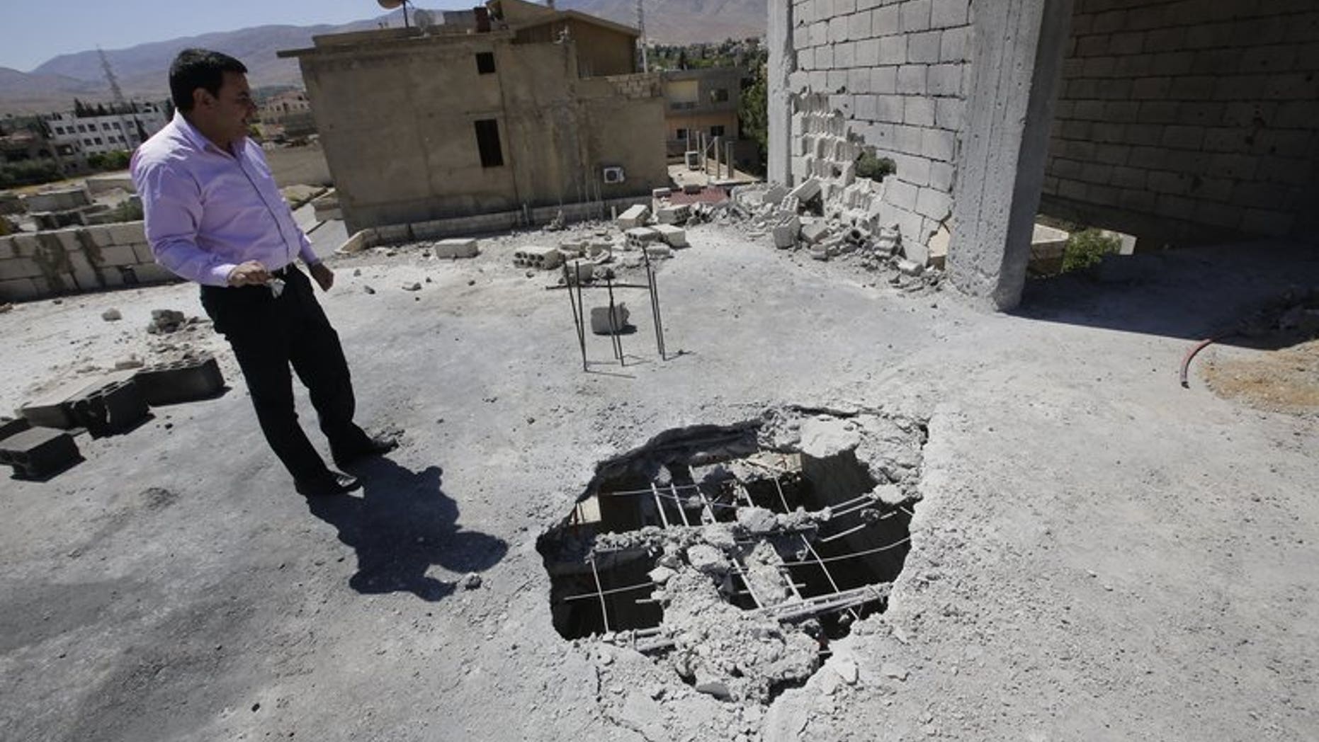 A Lebanese man inspects the damage after a rocket coming from Syria fell on his house in the town of Hermel, a few kilometres from Baalbek in the Bekaa valley, on April 26, 2013. Five rockets landed in and around the eastern Lebanese town of Hermel, a Hezbollah stronghold, on Sunday, a security source told AFP on condition of anonymity.