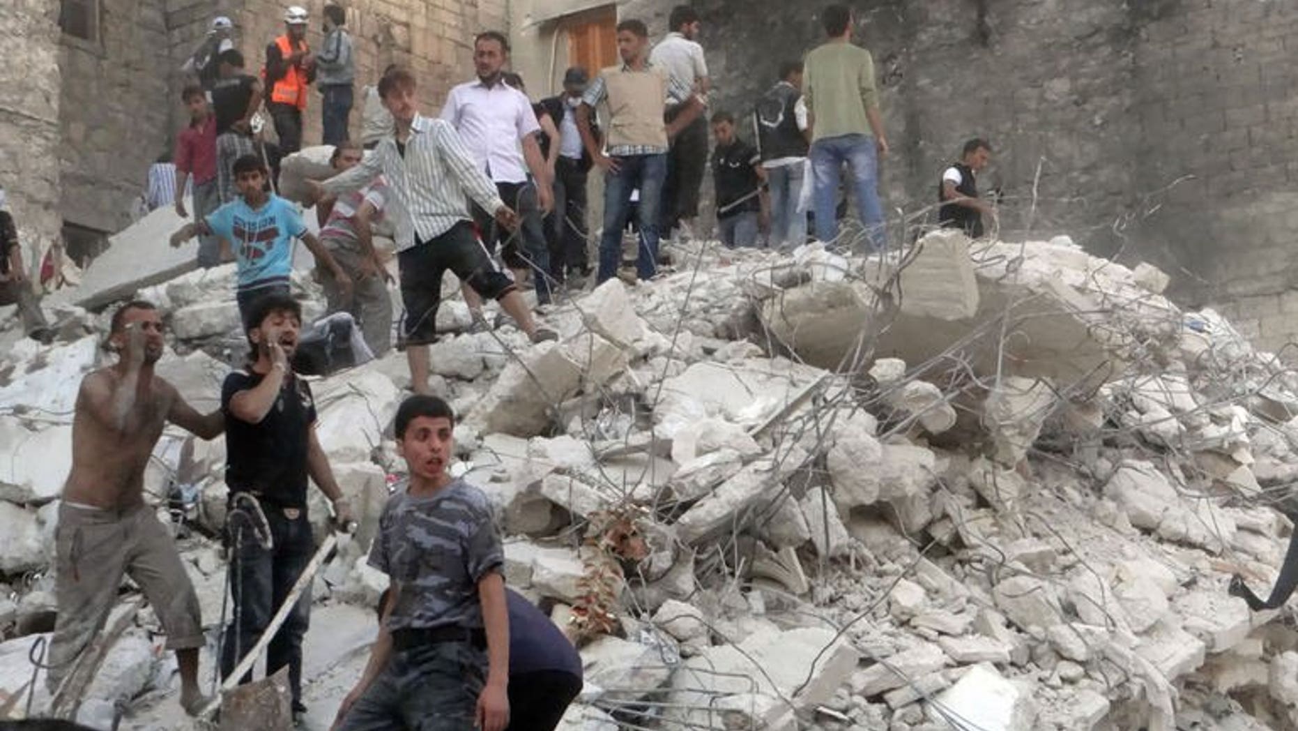 Men stand on debris from a building which collapsed after it was allegedly bombed on August 16, 2013 in Aleppo. Syria's President Bashar al-Assad said on Sunday he is determined to "eradicate terrorism" which he blames for the conflict raging in his country, according to state news agency SANA.