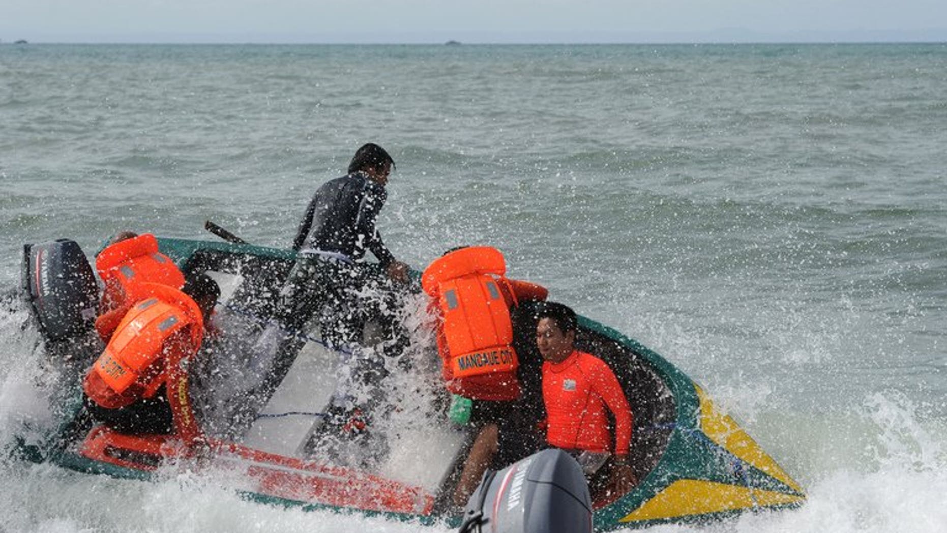 Volunteer rescuers struggle in big waves as they head to the site of a ferry crash near Cebu on August 18, 2013. The death toll from the disaster rose to 52 on Monday as more bodies were pulled from the water, the coastguard said.