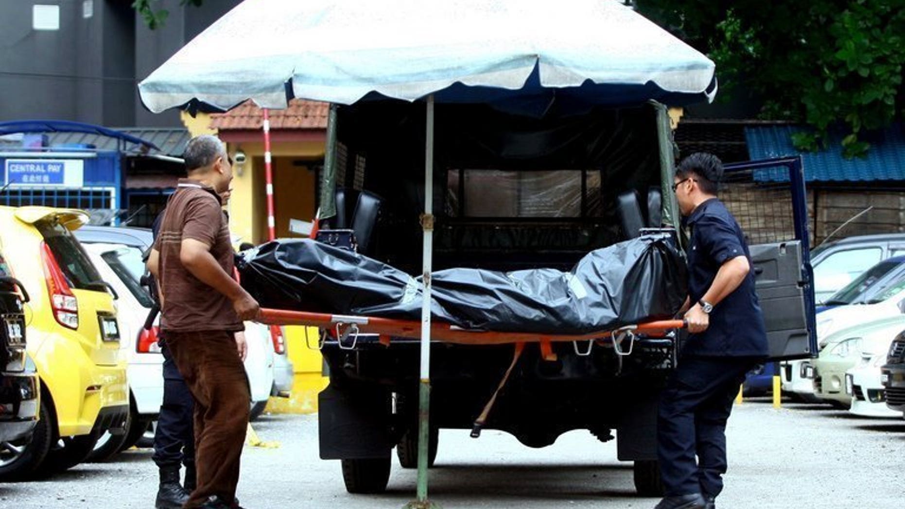 Picture taken on July 29, 2013 shows Malaysian forensic police carrying the body of late Arab Malaysian Banking Group founder Hussain Ahmad Najadi after he was shot dead on a street in Kuala Lumpur. Malaysian police said they killed five suspected gang members in a shootout early Monday and arrested 200 people in a crackdown on a spate of violent crime that has shocked the country.