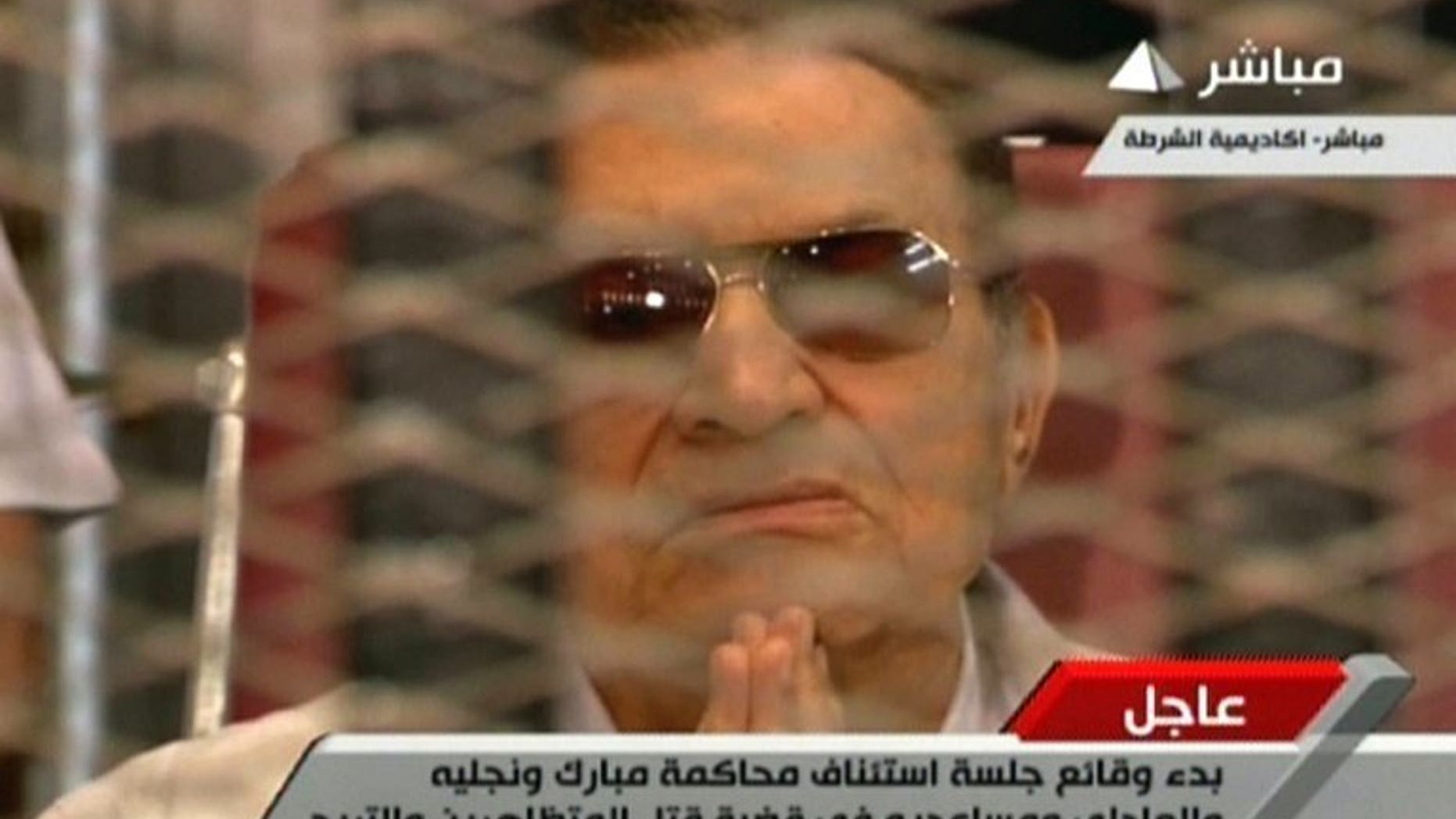 Image grab taken from Egyptian state TV shows ousted president Hosni Mubarak gesturing behind bars during a hearing in his retrial at the police academy in Cairo on July 6, 2013. Mubarak has been granted conditional release in one of the cases against him, but will remain in custody on charges in an additional case, judicial sources said Monday.