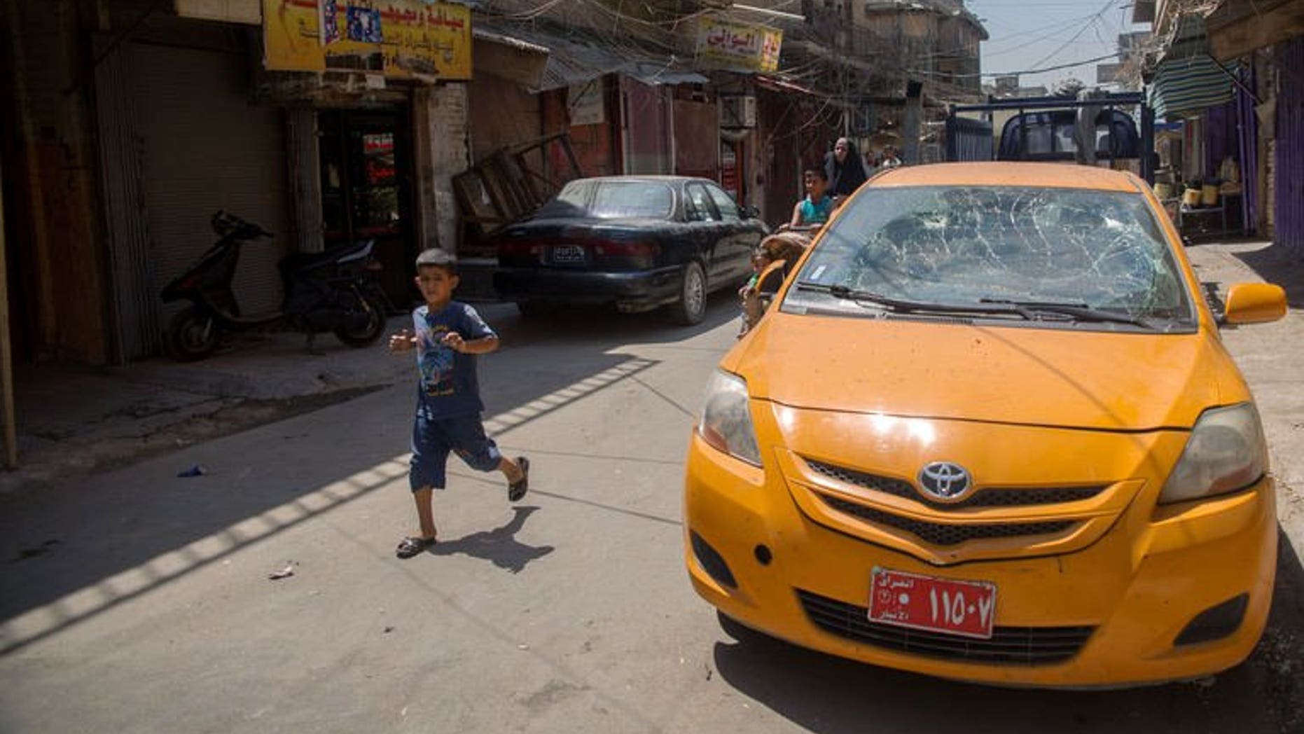 A boy runs past a taxi which was damaged by a bombing in the Allawi neighbourhood of central Baghdad on August 15, 2013. Attacks on Monday killed six people in Iraq, as gunmen defied massive government operations to stem some of the worst violence to have hit the country in five years.