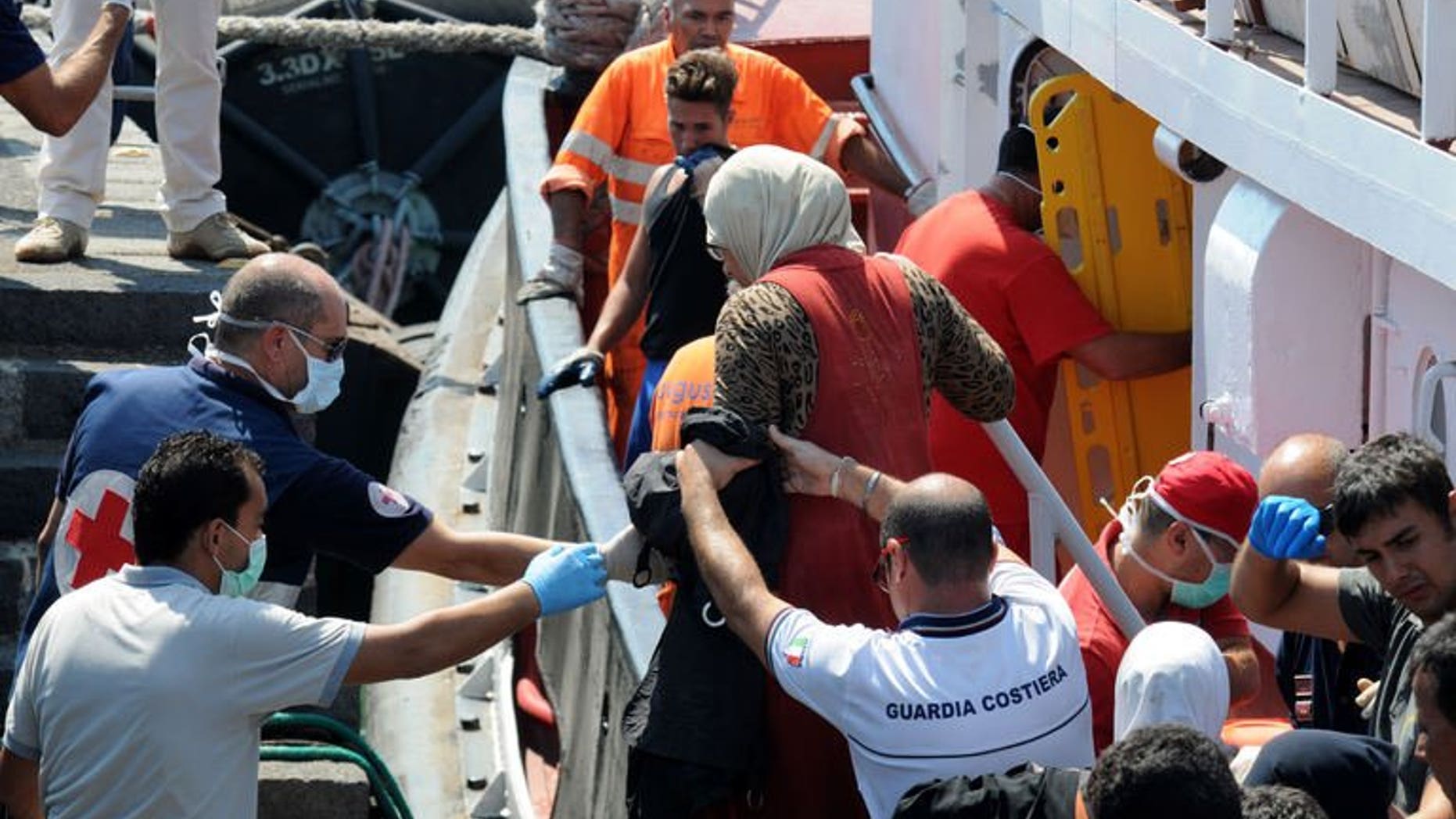 Coast guard help immigrants on August 19, 2013 in the Catania harbor after being rescued off the Italian coast. Four boats carrying more than 350 migrants including Egyptians and Syrians have landed in Italy, officials said Monday, the latest arrivals due to the growing unrest in north Africa.