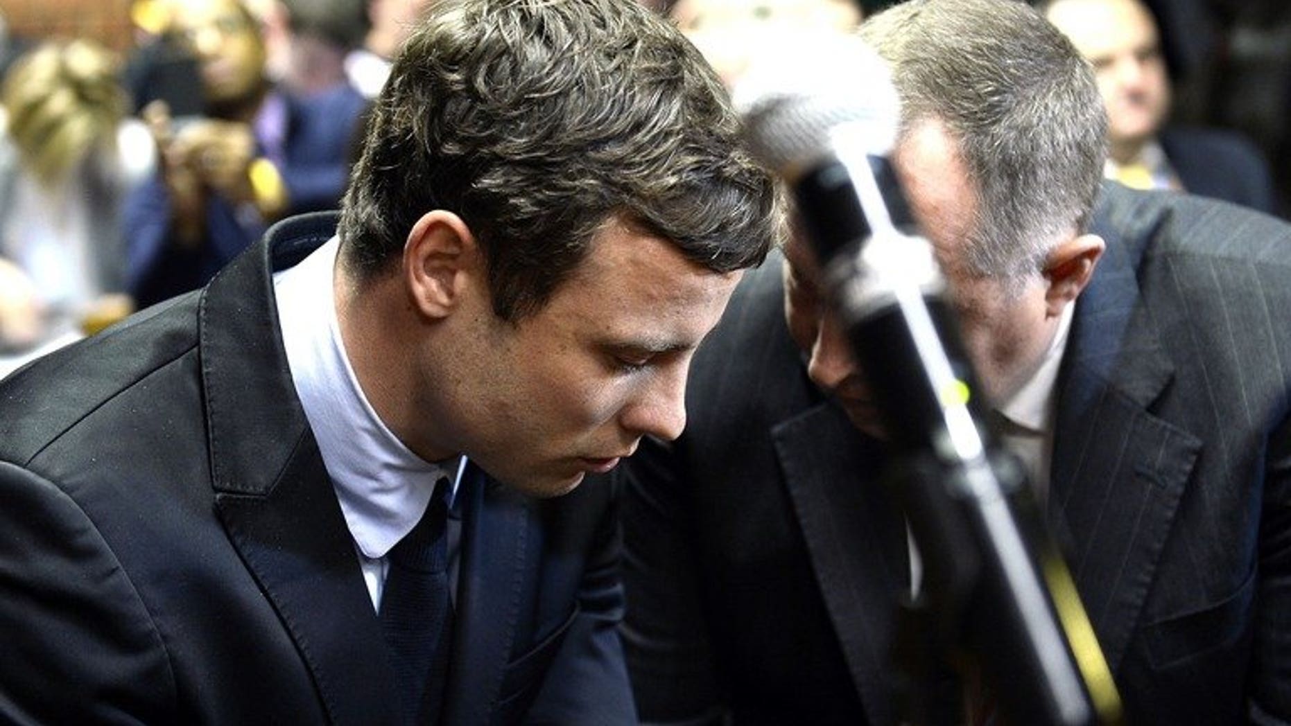 Oscar Pistorius (L) appears at Pretoria Magistrate's Court on August 19, 2013. South Africa's Paralympic sprint star has launched a bid to negotiate an out-of-court deal to pay damages to the parents of his lover whom he killed on Valentine's Day, a local newspaper says.