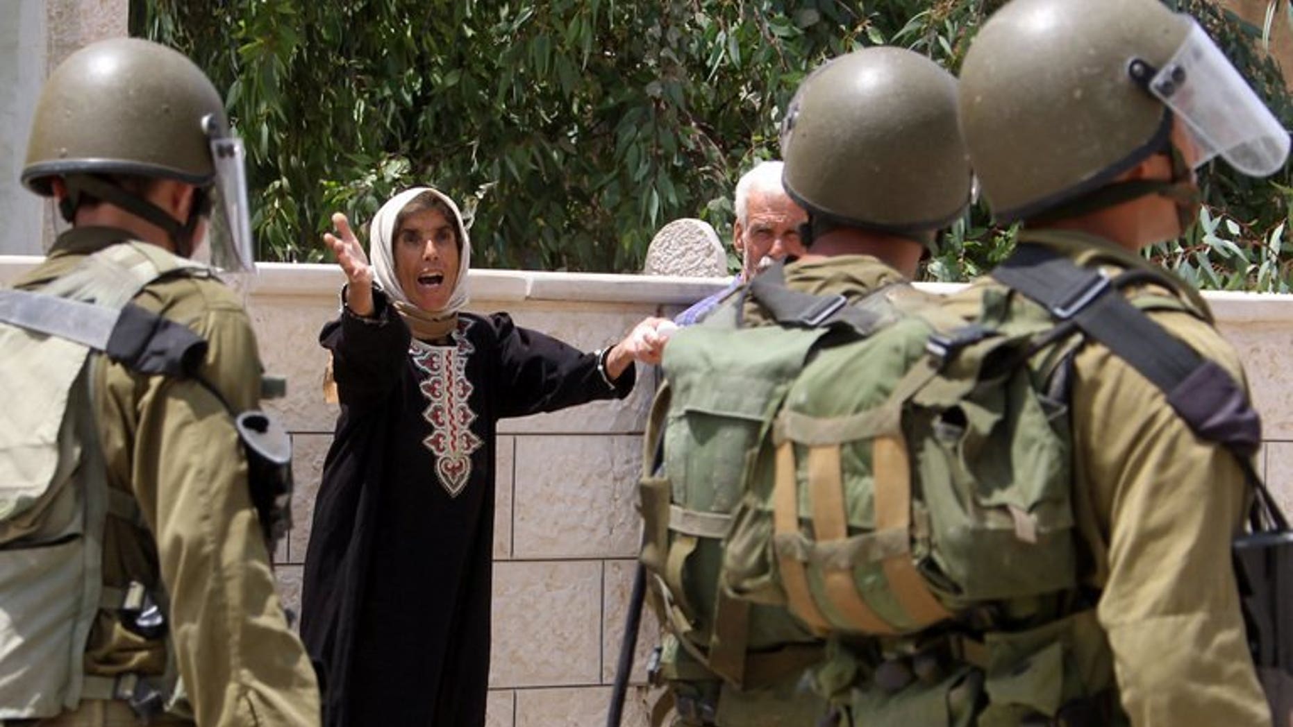 A Palestinian woman yells at Israeli soldiers during clashes following a protest in the village of Kfar Qaddum, near Nablus in the occupied West Bank on July 19, 2013. Israeli troops shot dead a Palestinian and wounded two others during an operation early Tuesday to arrest a Palestinian militant in the West Bank city of Jenin, the army said.