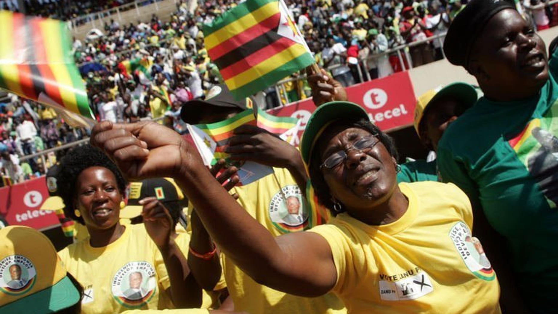 Supporters of Zimbabwe's President Robert Mugabe wave flags upon his arrival at the commemoration of Defence Forces Day in Harare on August 13, 2013. Zimbabwe's constitutional court on Tuesday ruled that a disputed elections which handed Robert Mugabe five more years in power were free and fair, dismissing allegations of vote-rigging.
