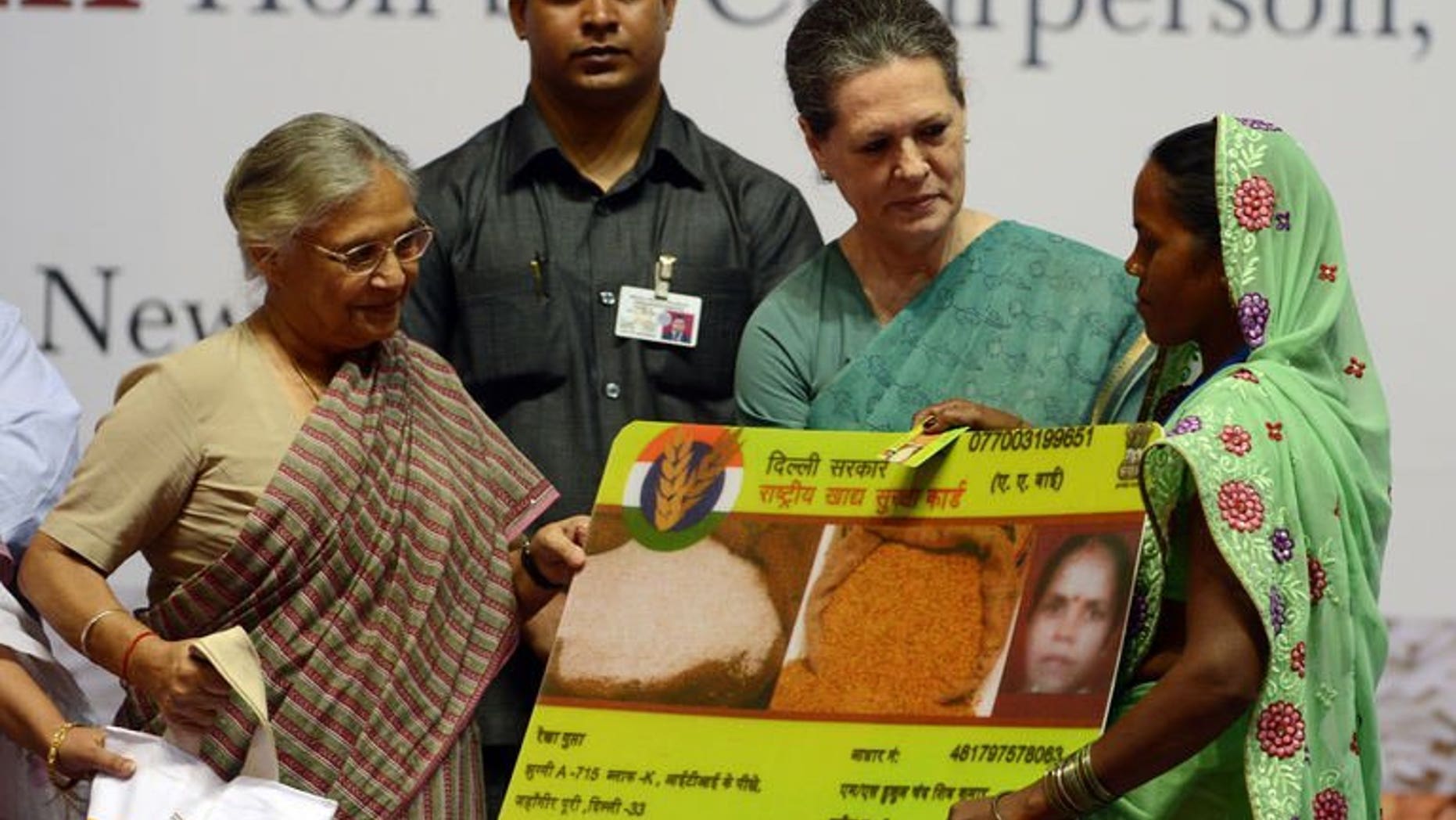 India's ruling Congress party chief Sonia Gandhi (2L) presents a woman with an ceremonial food card as Delhi Chief Minister Sheila Dixit (L) looks on during the launch of the Food Security Programme in New Delhi, August 20, 2013. Gandhi on Tuesday launched the landmark public food scheme for hundreds of millions of people, declaring it would banish hunger and be free of corruption.