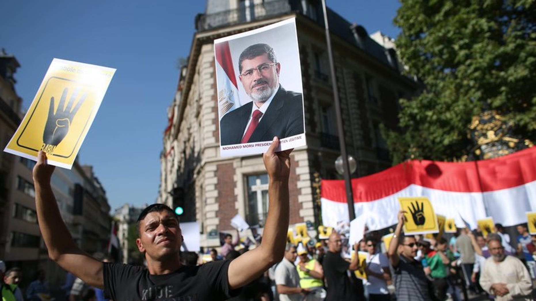 A protester holds a placard reading "R4BIA" (L) and a poster of Egypt's ousted president Mohamed Morsi during a protest against army-installed Egyptian government, in front of the Saudi Arabia's embassy in Paris, on August 20, 2013. Europe stood poised to firmly condemn the blistering violence in Egypt but stop short of sanctions as EU foreign ministers gathered Wednesday.