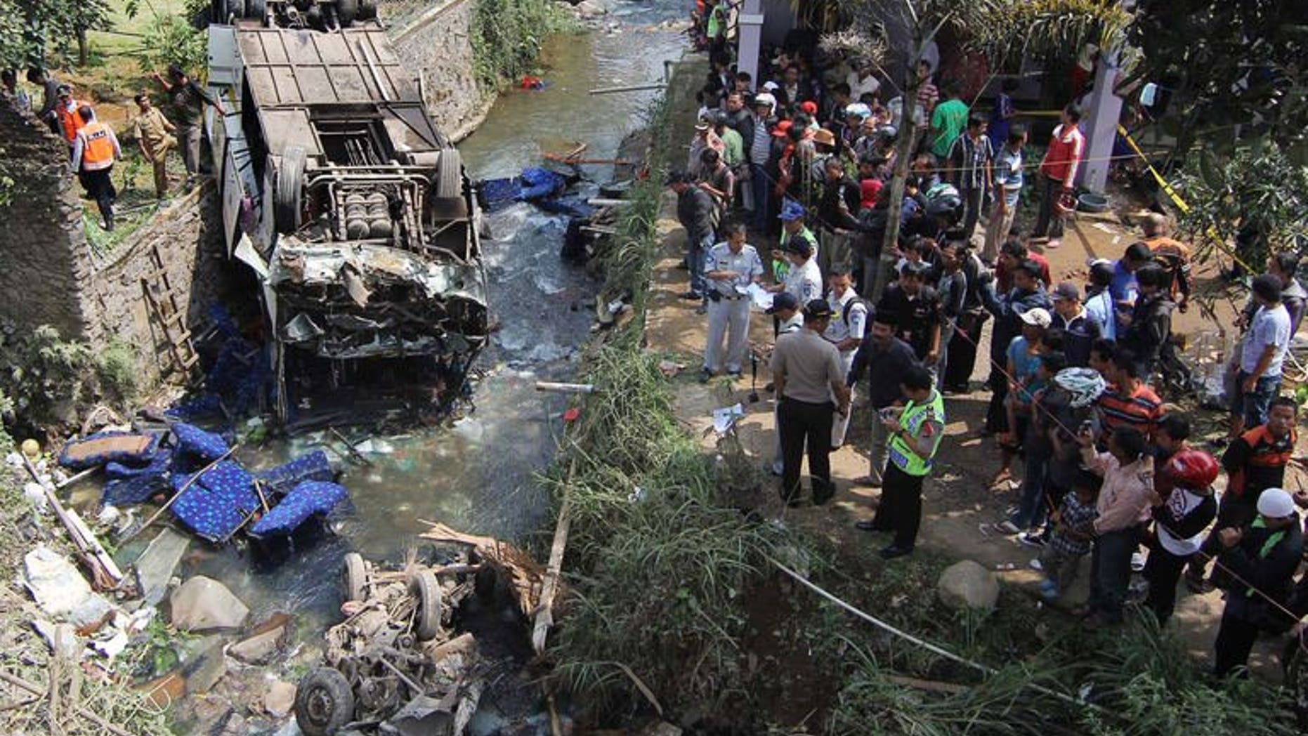 Indonesian police and officials examine the scene of an accident after a bus (L) plunged into a river in Cisarua, Bogor, in West Java on August 21, 2013. Eighteen people were killed and dozens injured Wednesday when a bus plunged into a river as it returned from a church outing on Indonesia's main island of Java, police said.